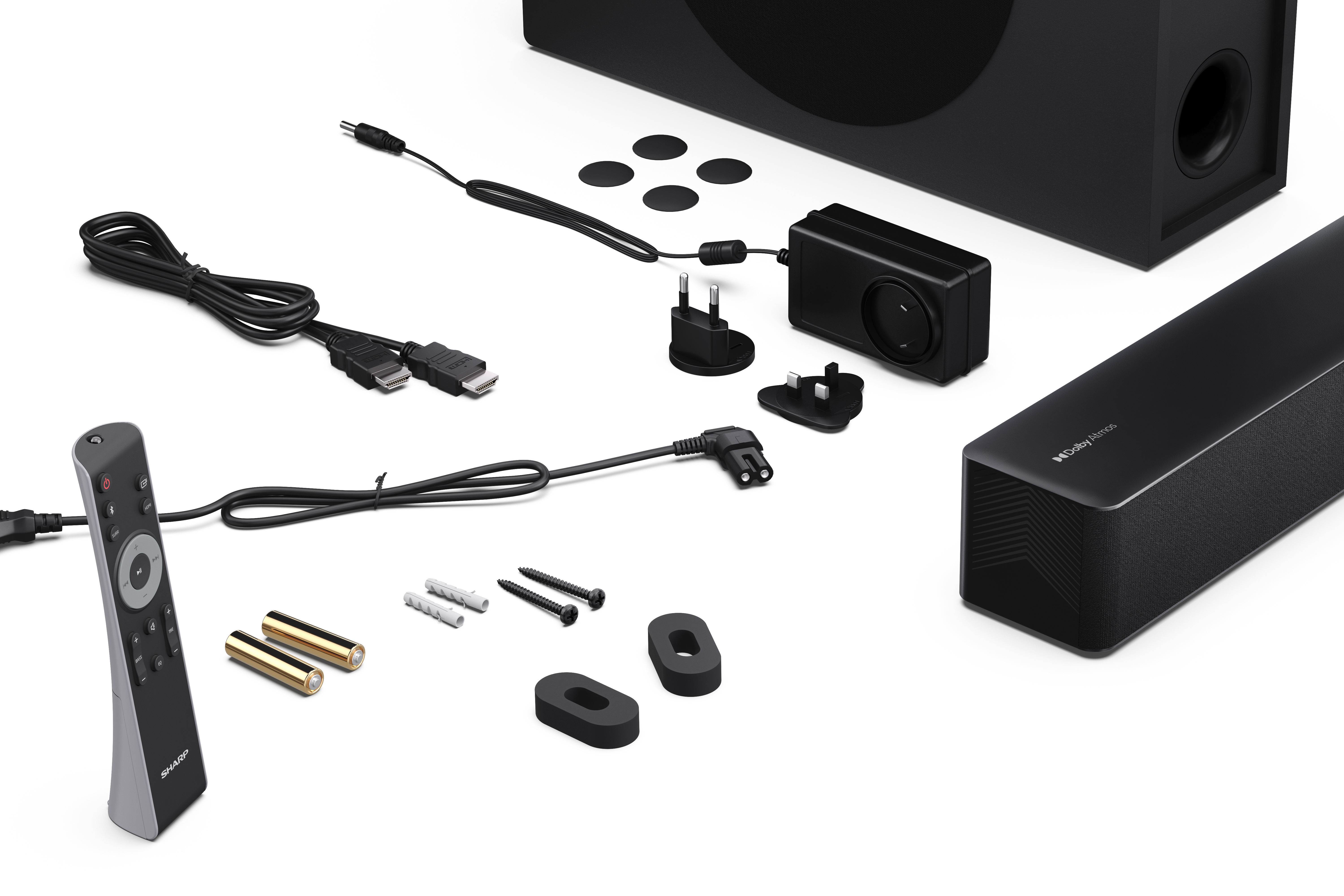 Fekete soundbar, mélynyomó, távirányító, kábelek, hálózati adapterek, csavarok és egyéb kiegészítők fehér felületen.