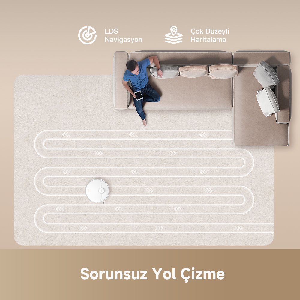 Bir robot süpürge halı üzerinde bir yol izliyor. Bir adam kanepede oturuyor. Yukarıdan görünüm.
