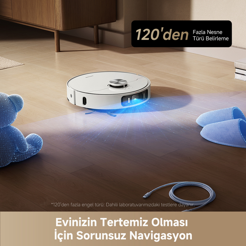 Ahşap zeminde beyaz bir robot süpürge. Mavi bir oyuncak ayı ve terlikler yakınında. Türkçe metin mevcut.
