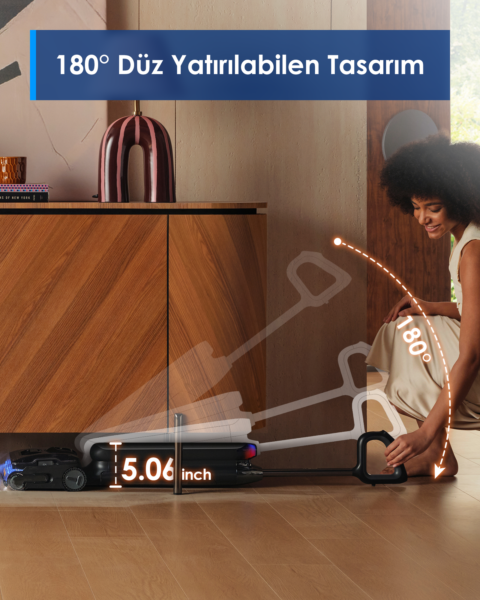 Bir kadın siyah bir elektrikli süpürge kullanıyor. Ürün düz durabilir ve 5,06 inçtir. Arka plan mobilyaları içerir.