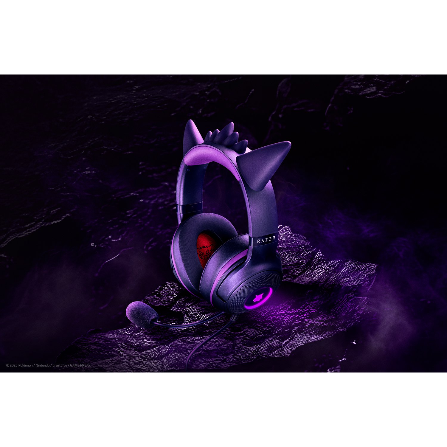 Een paarse Razer-headset, ontworpen met Gengar-oren, ligt op een getextureerd oppervlak. De headset heeft een microfoon en het Razer-logo is zichtbaar.