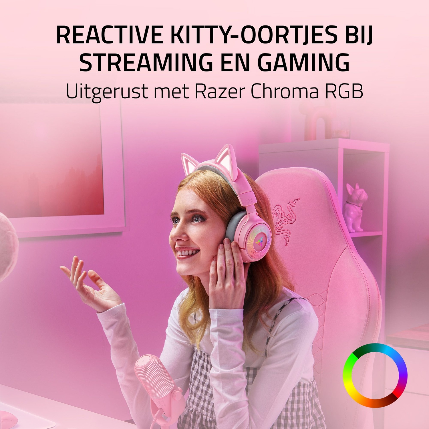 Une femme portant un casque à oreilles de chat sourit. Elle est assise sur une chaise rose, tenant un microphone rose. Le fond est rose.