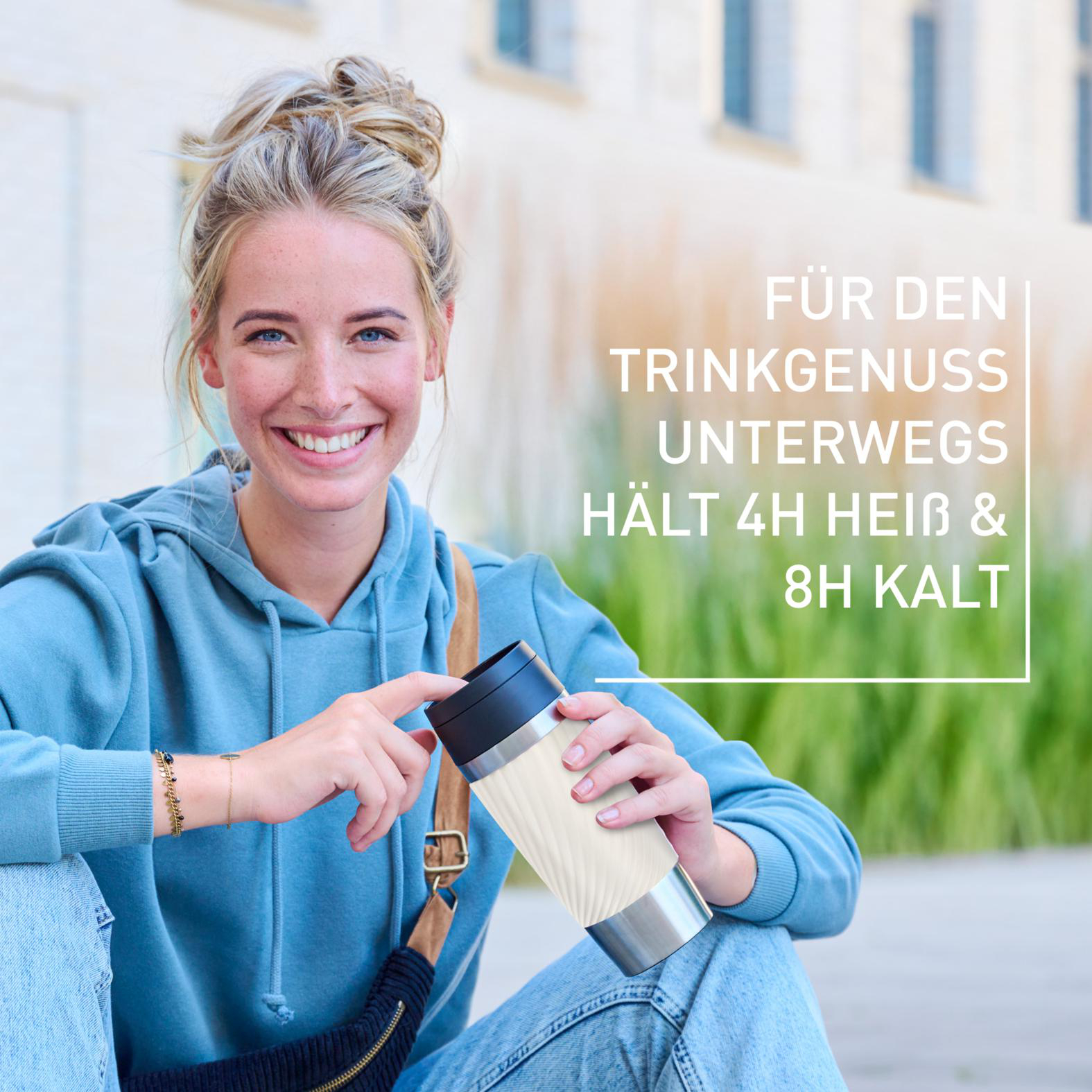Junge Frau lächelt und hält einen Reisebecher. Text: Für Trinkgenuss unterwegs, hält 4h heiß & 8h kalt.