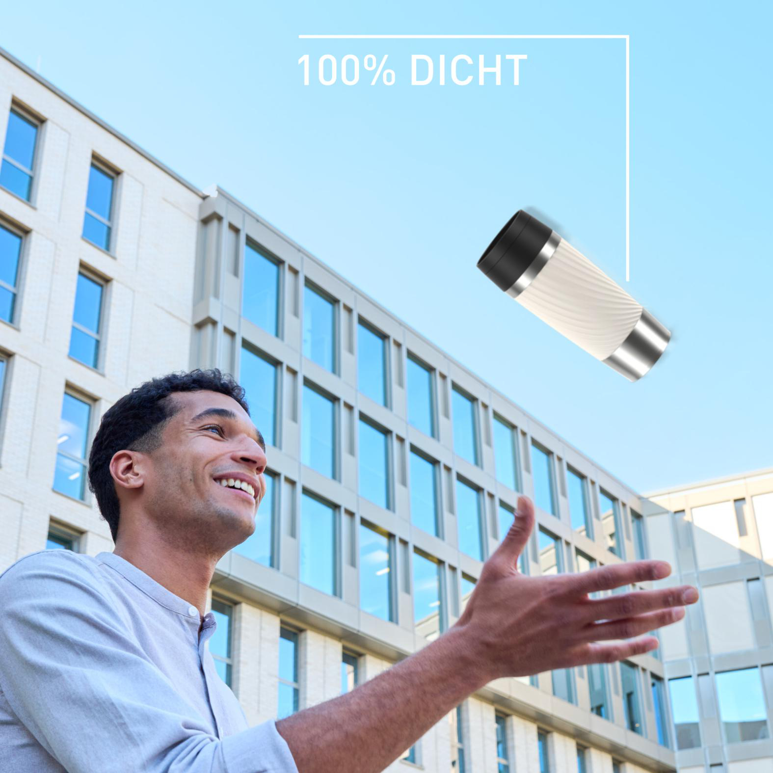 Ein Mann lächelt und greift nach einem weißen Reisebecher, der in der Luft schwebt. Gebäude und blauer Himmel im Hintergrund.