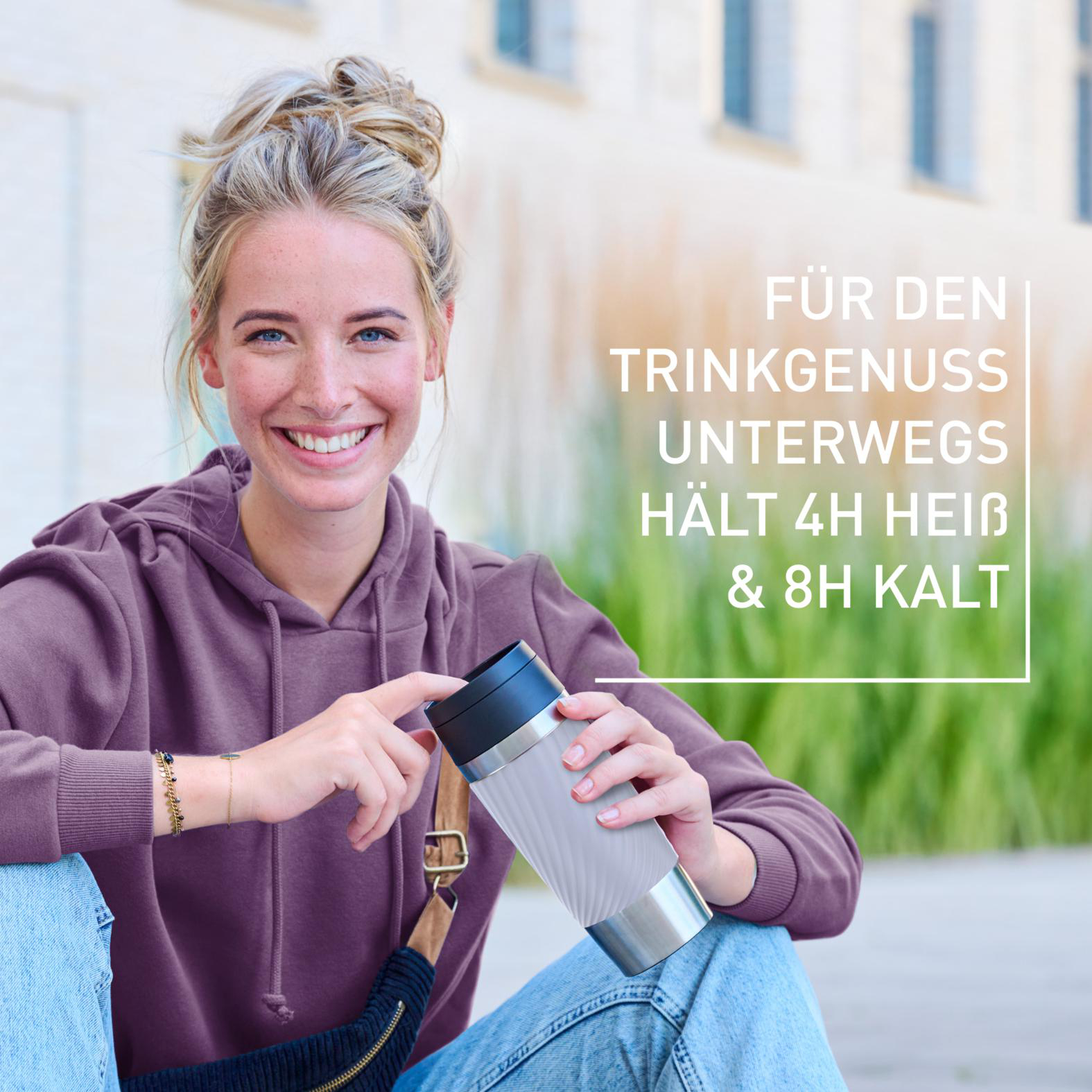 Eine Frau lächelt und hält einen Reisebecher. Text: 'Für Trinkgenuss unterwegs, hält 4h heiß & 8h kalt.'