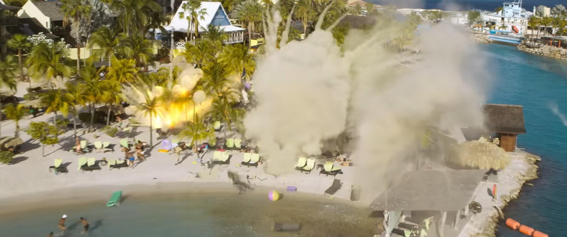 Strandszene mit Explosion. Palmen, Sonnenschirme und Menschen am Strand. Rauch und Trümmer trüben den Himmel über dem Wasser.