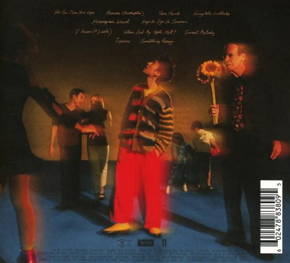 Albumcover: Ein Mann in roter Hose blickt nach oben. Andere sind verschwommen. Ein Mann hält Sonnenblumen. Text oben.