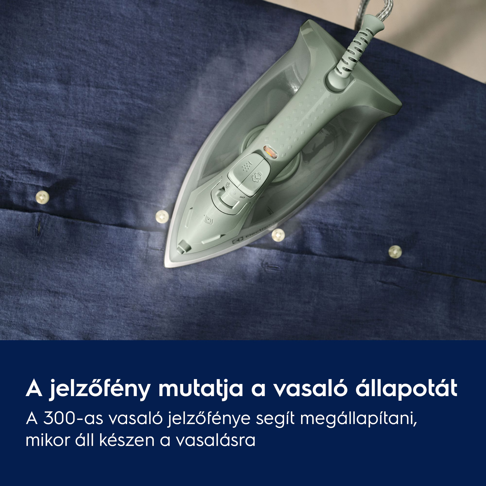 Vas a kék ing felett. A vasaló szürke. Látható gőz. Aingen gombok vannak.