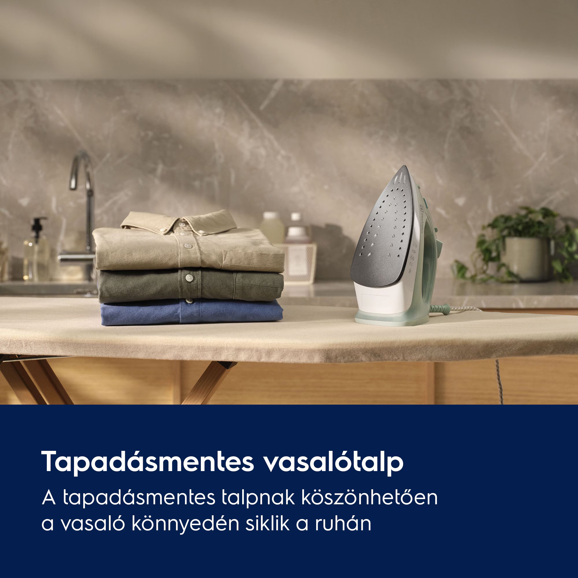 Vasaltódeszka vasalóval. A deszkán halmozott ingek. A háttérben mosogató és növény.