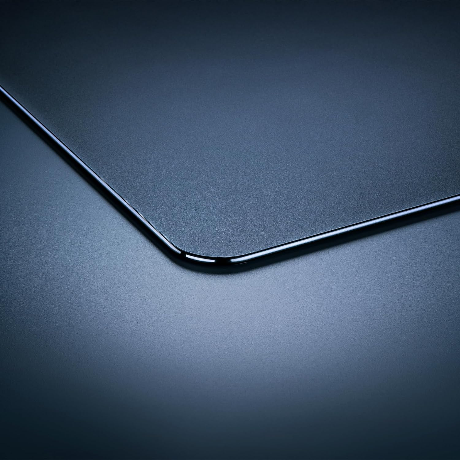 Gros plan d'une surface bleu foncé mate avec un coin arrondi. Un bord noir brillant encadre le bord.