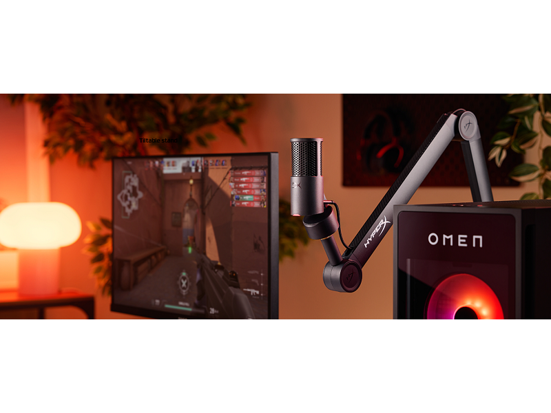 Egy játékbeállítás monitorral, mikrofonnal és számítógéppel. A monitor egy játékot jelenít meg. A mikrofon egy karra van rögzítve.