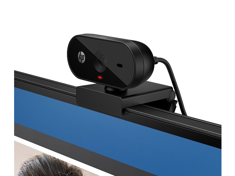 Fekete HP webkamera egy monitorhoz rögzítve. A webkamerán piros fény és logó található. Kék képernyő látható.