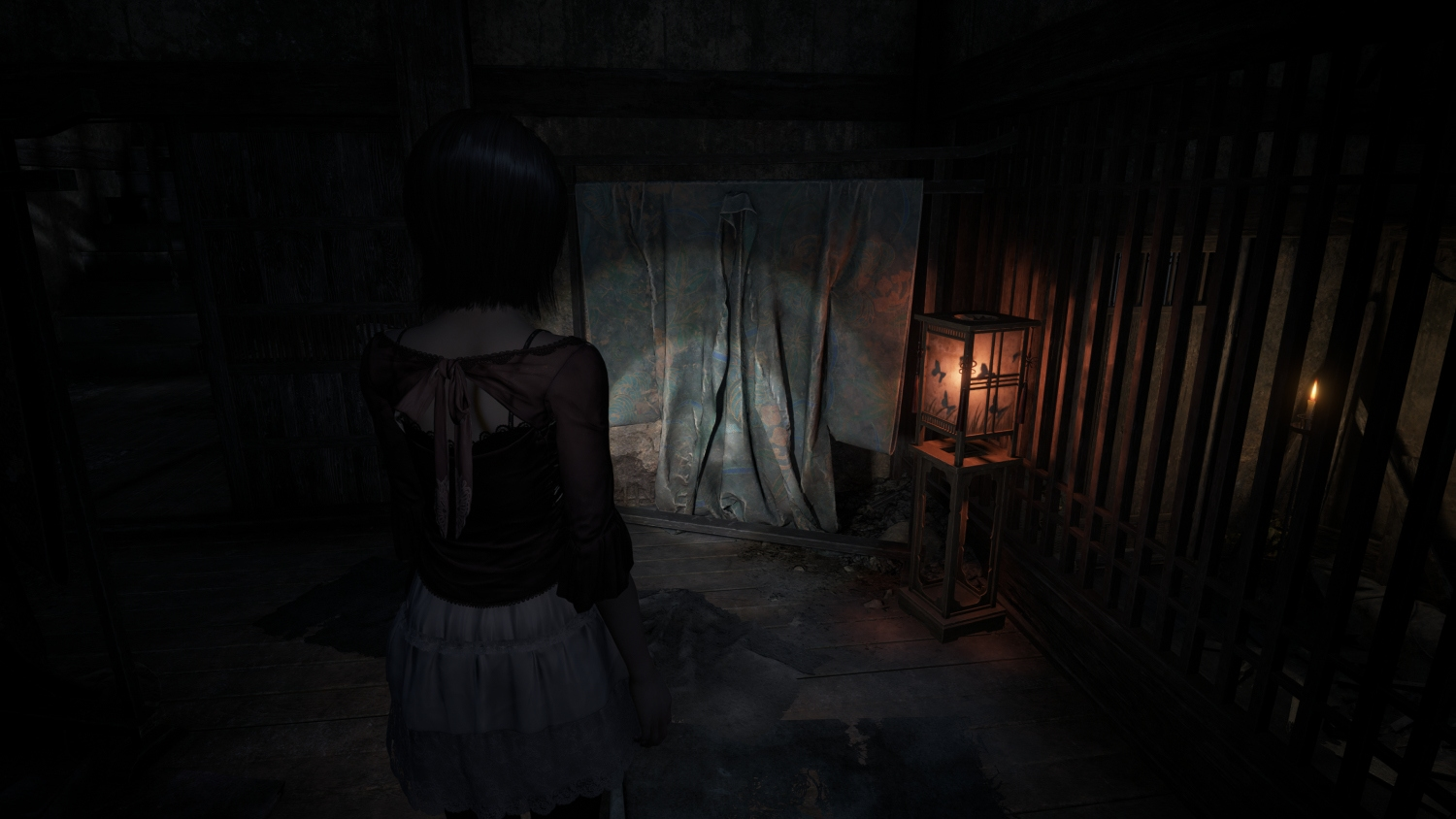 Una donna si trova in una stanza scarsamente illuminata, di fronte a una tenda. Una lanterna e una candela forniscono l'unica luce. La scena è oscura e misteriosa.