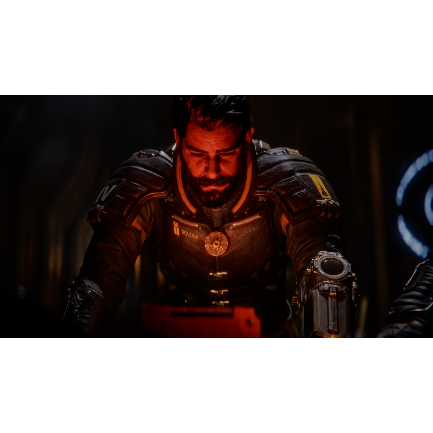 Un homme en uniforme sombre regarde vers le bas. Il a une barbe et porte une tenue futuriste. Le fond est sombre.