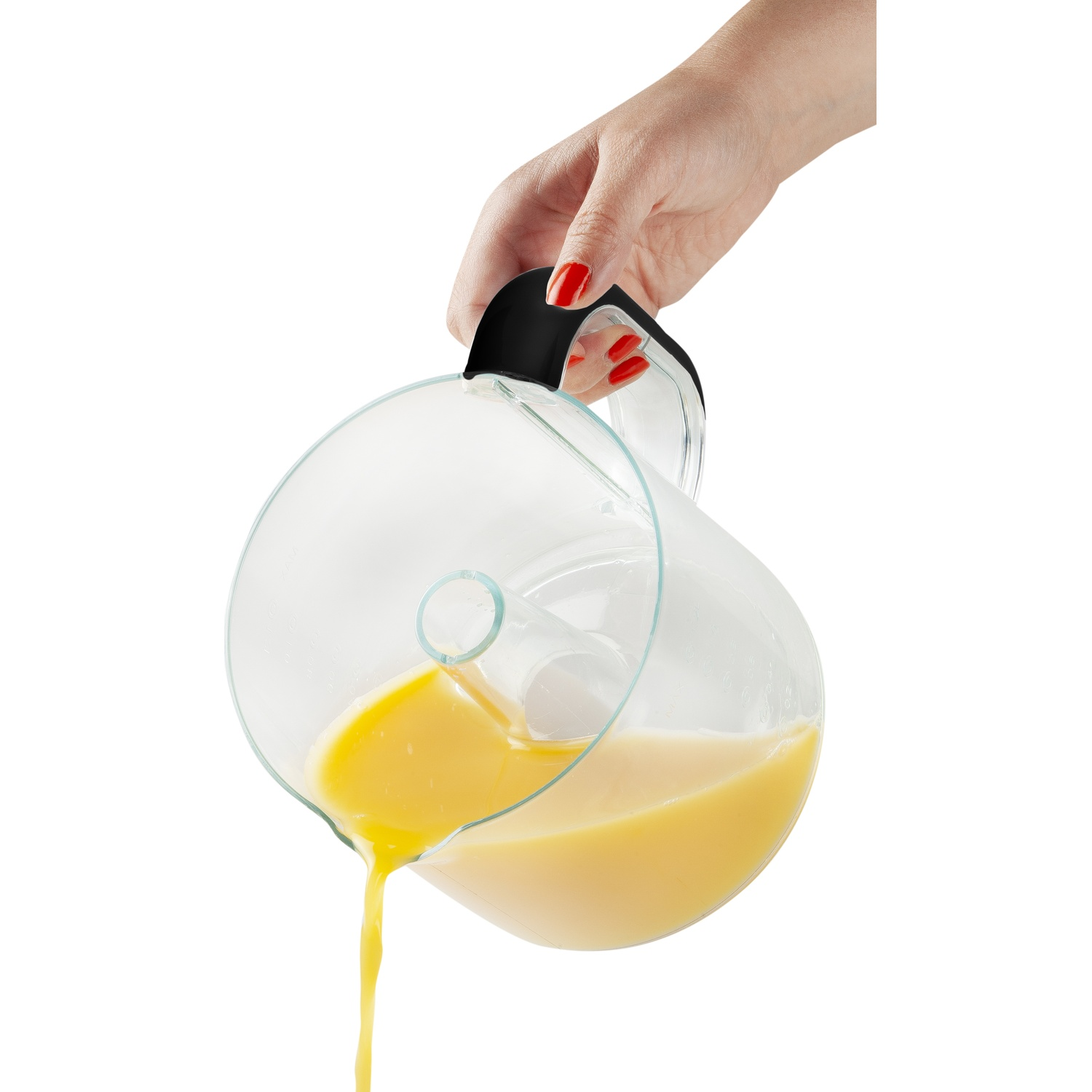 A hand pours orange juice from a clear pitcher with a black handle. The juice streams out against a white background.