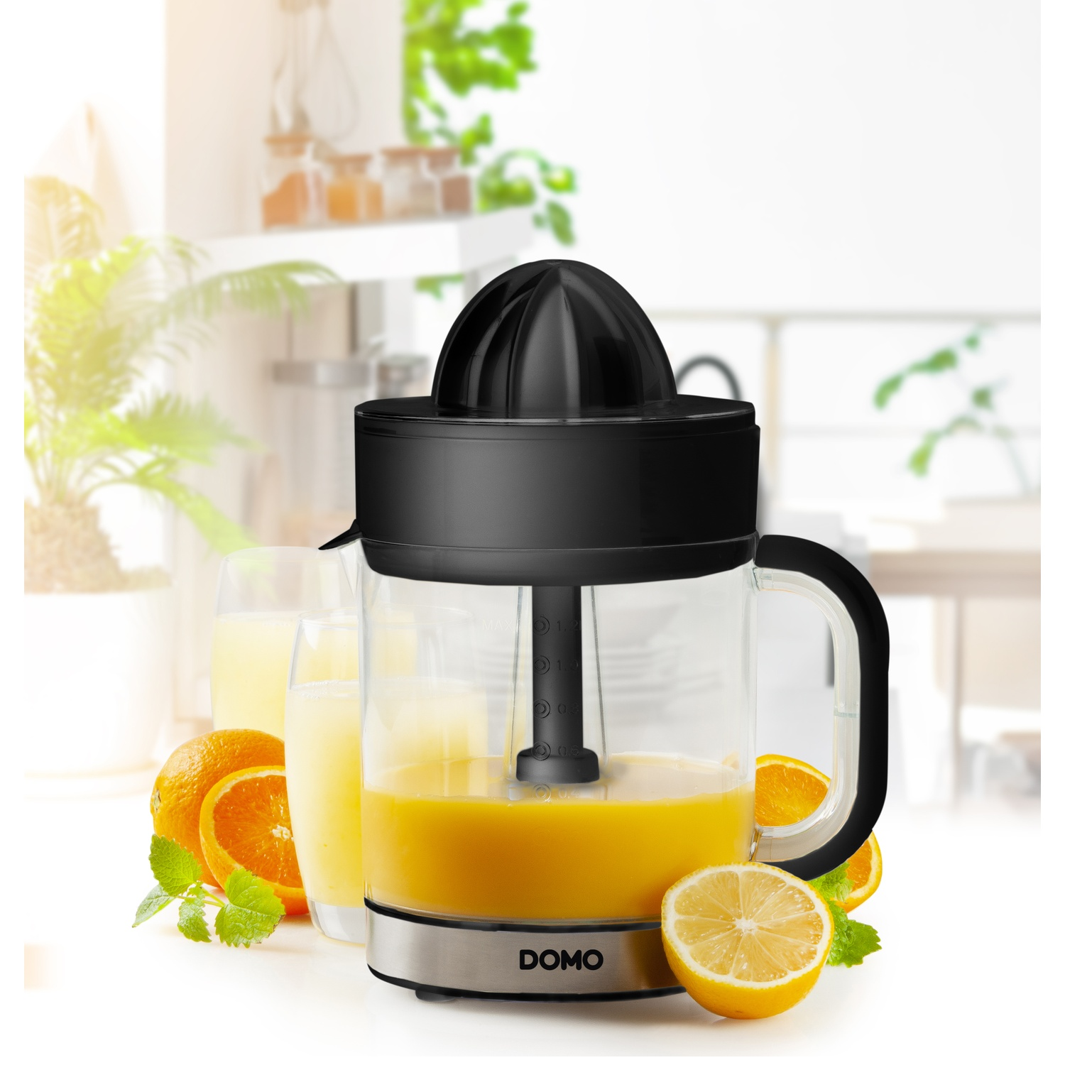 Electric juicer with oranges, lemon, and juice. Black and silver juicer with a glass container. Kitchen background.