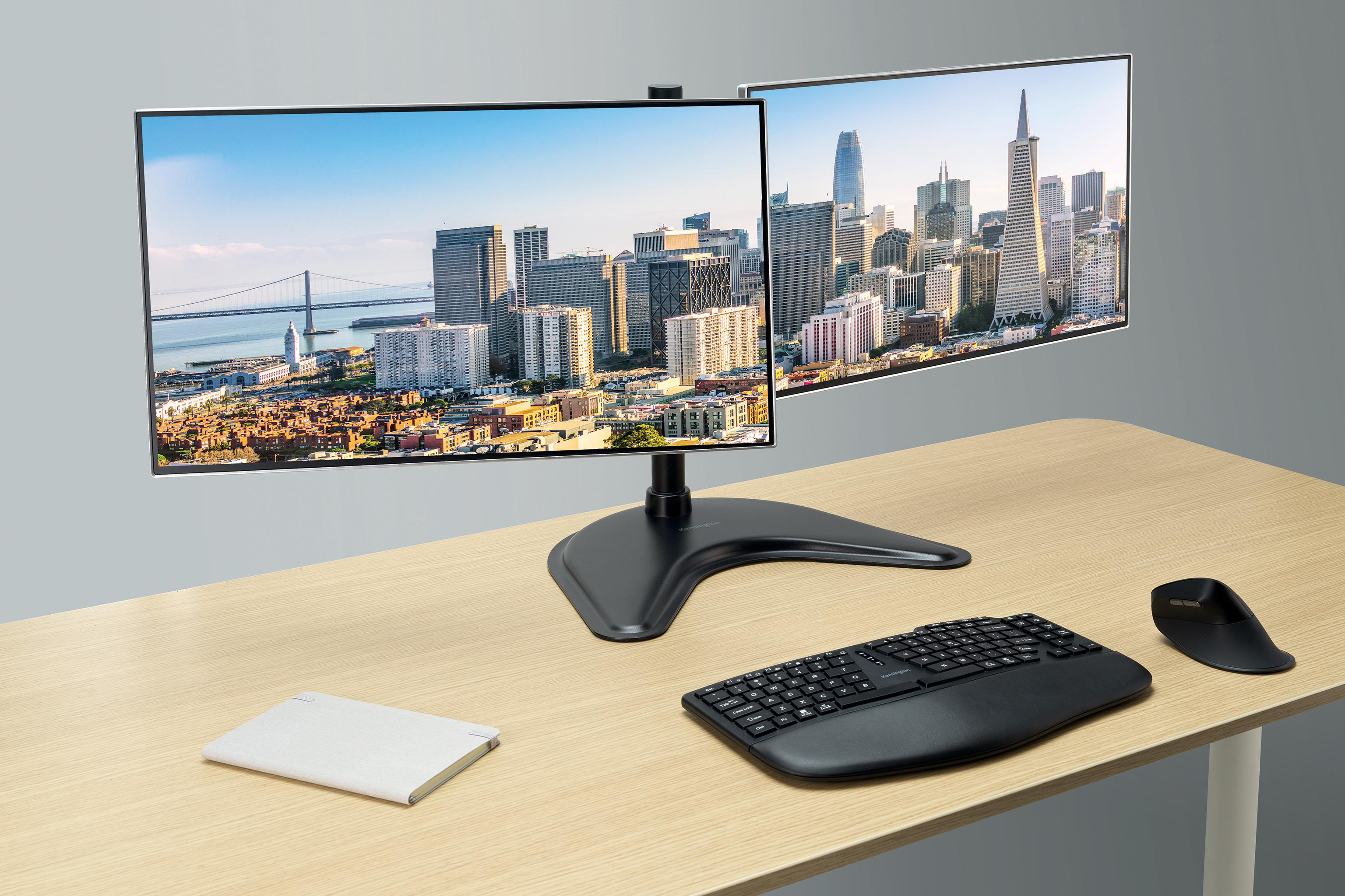 Zwei Monitore zeigen Ansichten von San Francisco. Tastatur, Maus und Pad stehen auf einem Holztisch. Grauer Hintergrund.