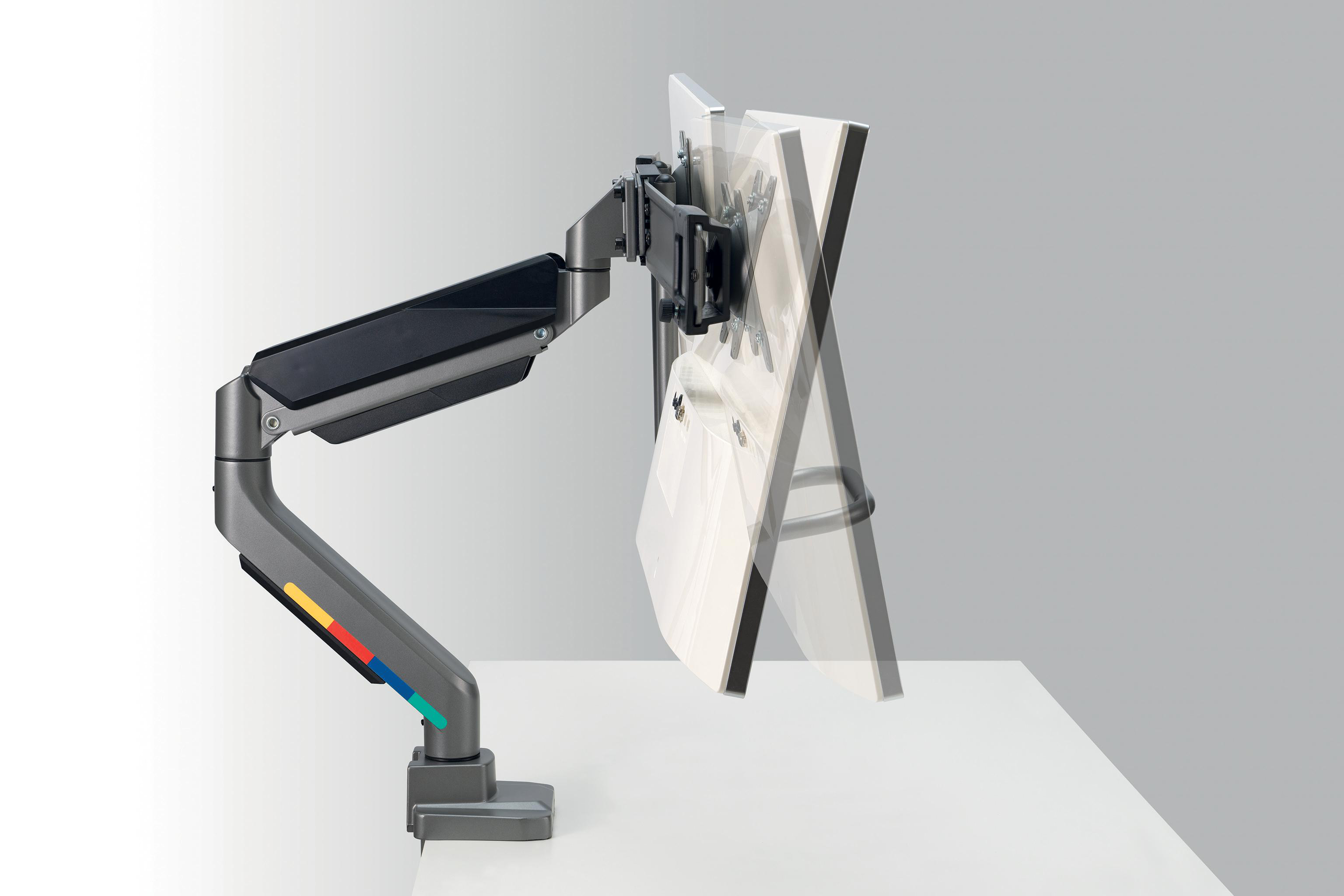 Ein Monitorarm mit Bildschirm steht auf einem weißen Schreibtisch. Der Arm ist grau mit farbigen Streifen. Der Hintergrund ist hellgrau.