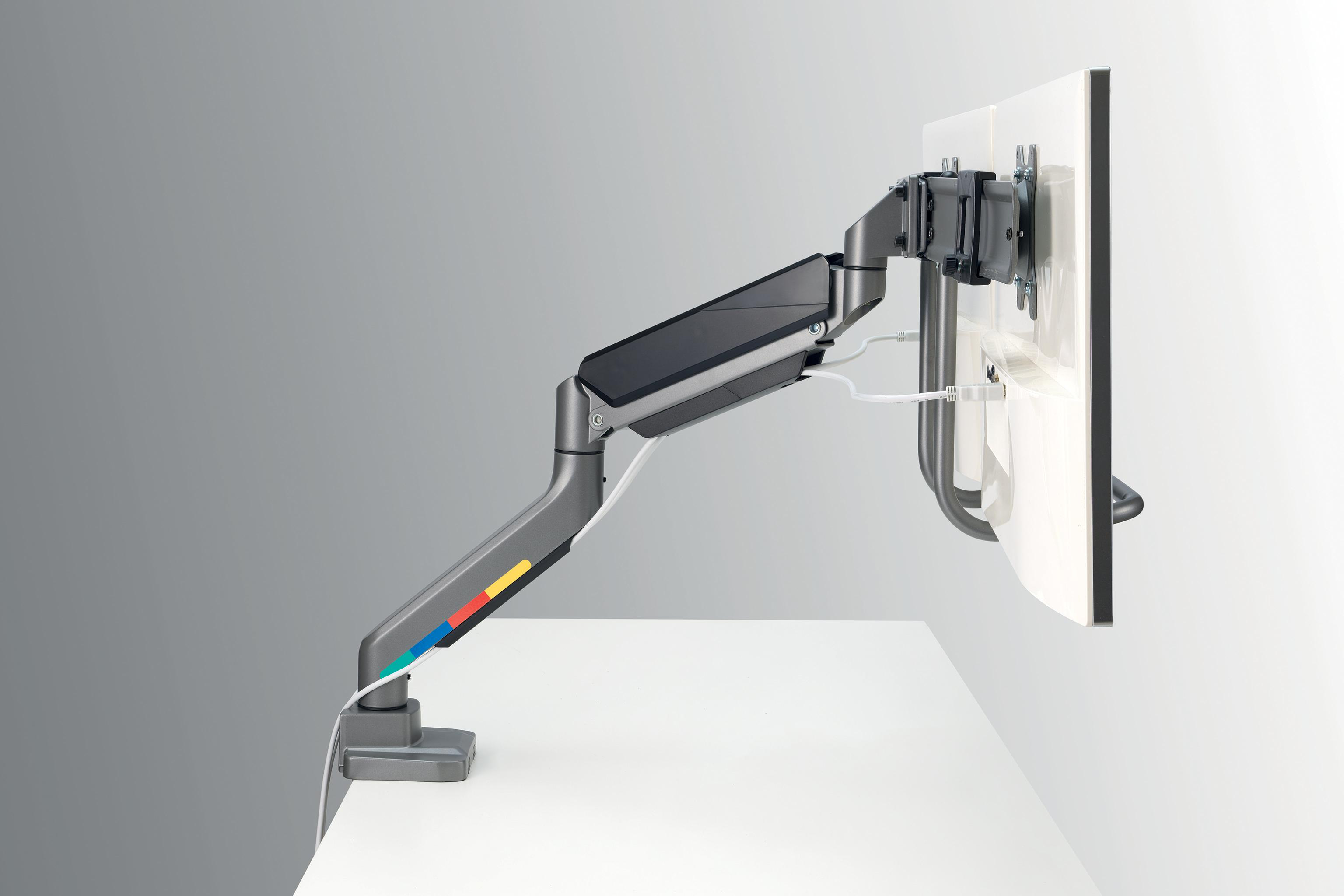 Monitorarm, der einen Bildschirm hält. Weißer Schreibtisch und Wand. Arm hat farbcodierte Akzente.