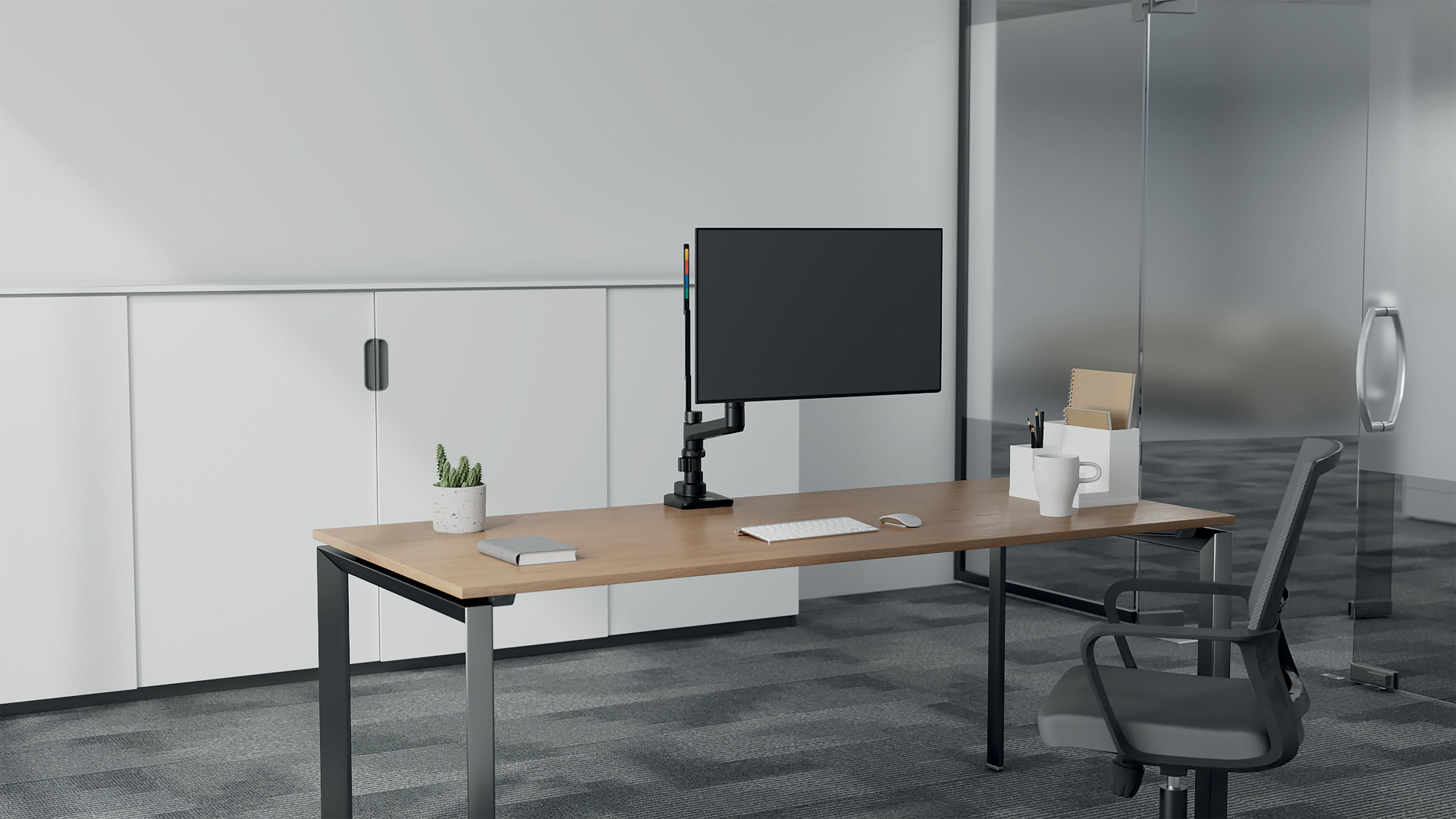 Schreibtisch mit Monitor, Tastatur, Maus, Becher und Pflanze. Ein Stuhl steht vor einer Glastür. Weiße Schränke im Hintergrund.