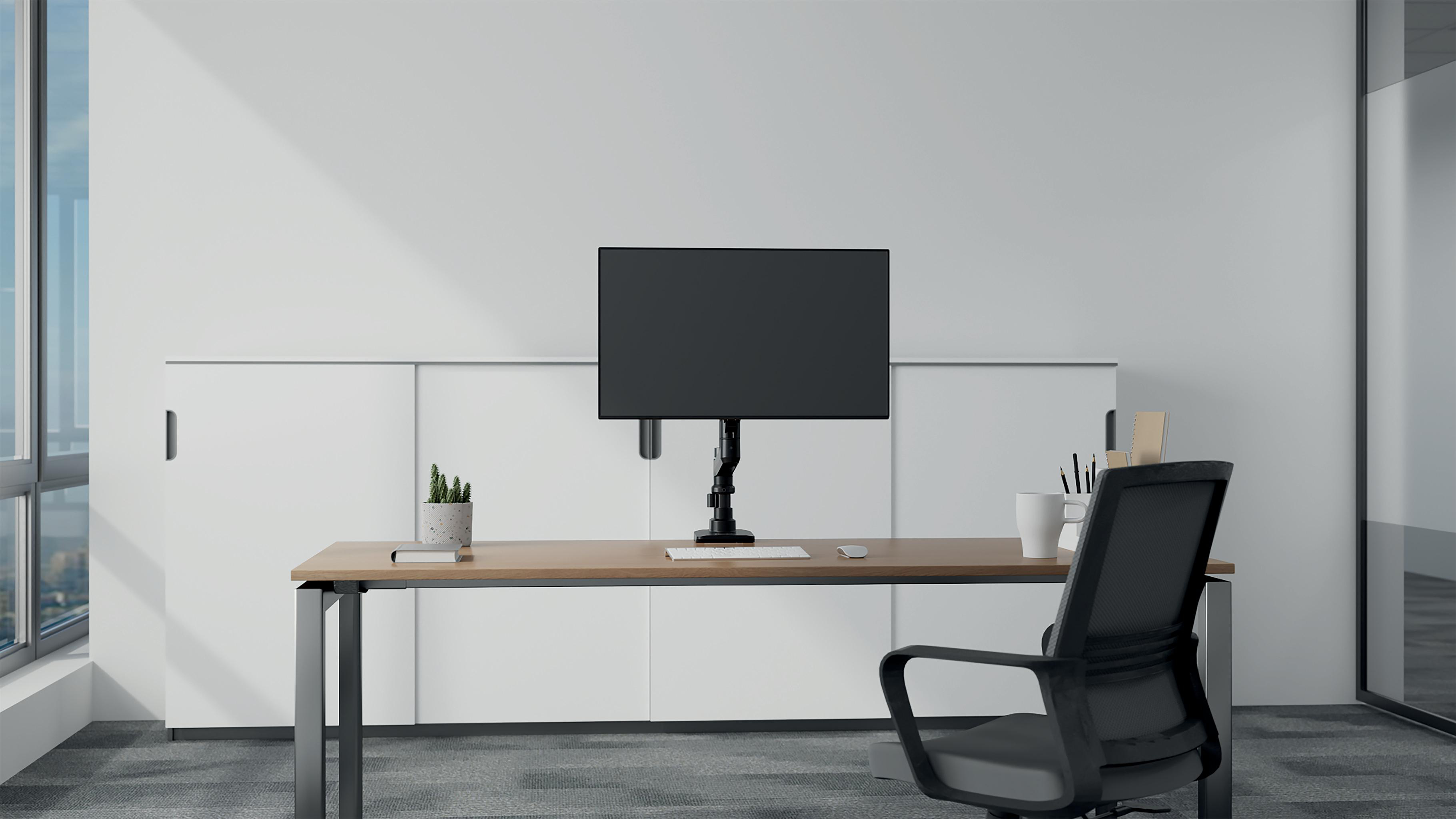Büro mit Schreibtisch, Monitor, Stuhl und Fenster. Eine Pflanze, ein Becher und andere Schreibwaren befinden sich auf dem Schreibtisch.