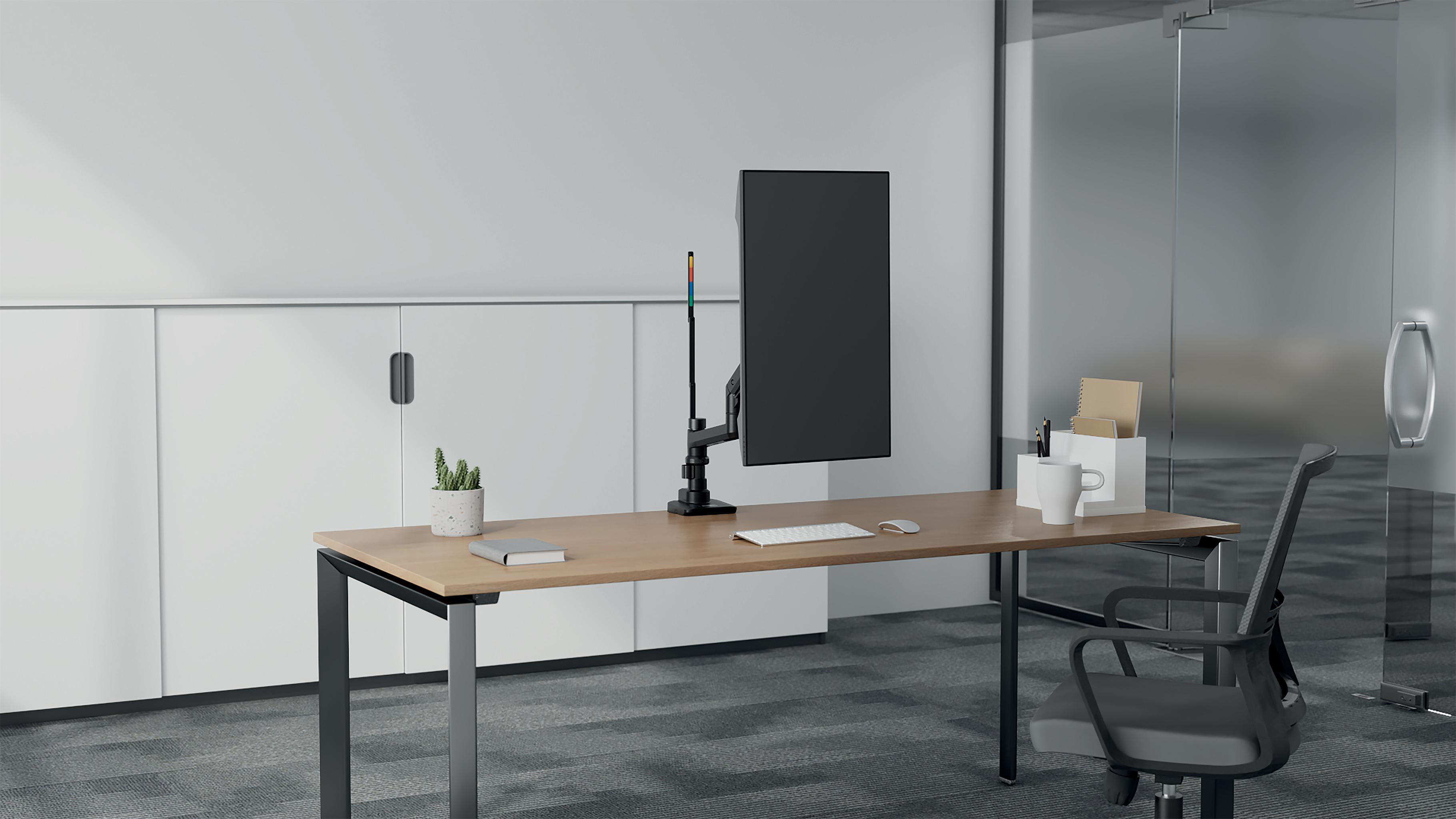Büroszene mit Schreibtisch, Monitor, Stuhl und Zubehör. Rechts eine Glastür und links weiße Schränke.