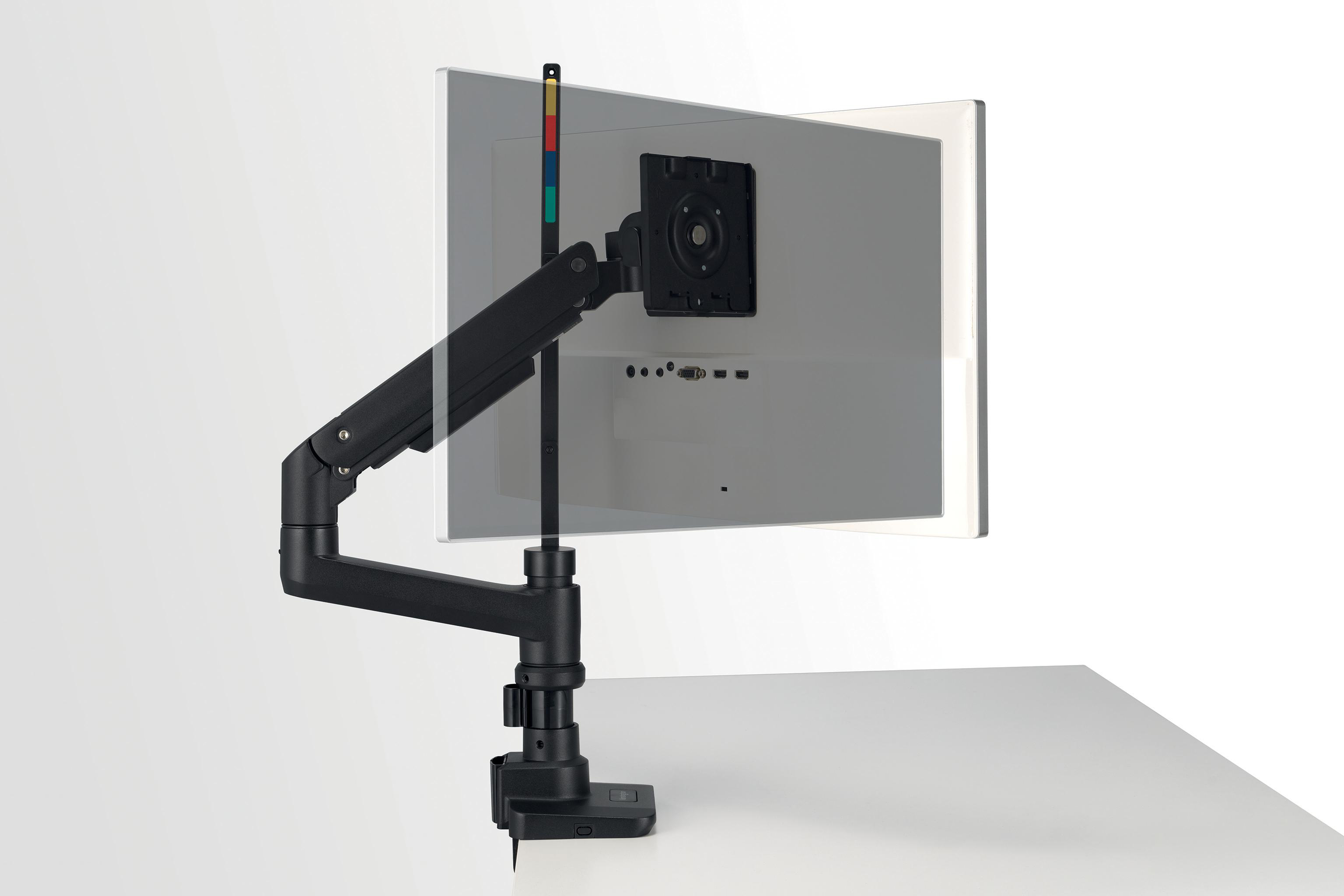 Monitor an schwarzem Arm montiert, Schreibtisch im Vordergrund, weißer Hintergrund. Farben am Arm.