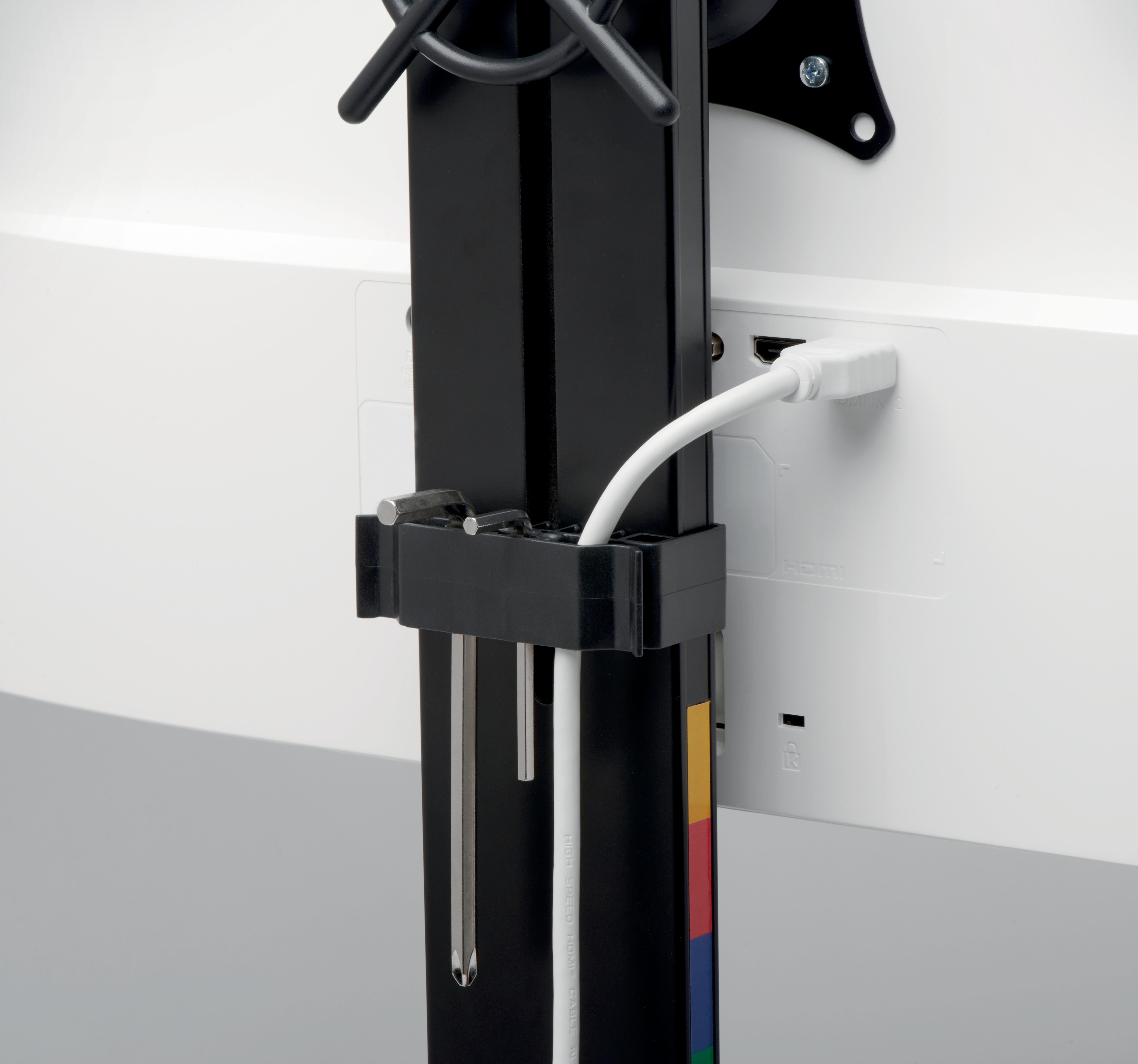 Nahaufnahme einer Monitorhalterung, schwarzer Rahmen mit weißem Kabel und weißem Monitor. Farben: Schwarz, Weiß und Primärfarben.