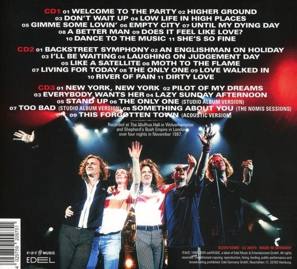 Band auf der Bühne. Fünf Männer mit erhobenen Händen. Album-Trackliste im Hintergrund. Bühnenlichter beleuchten die Szene.