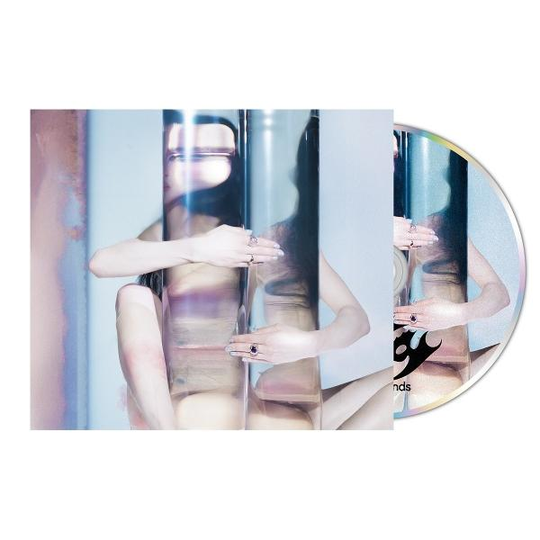 CD-Cover mit Frau hinter reflektierendem Glas. Sie trägt Ringe. CD zeigt etwas Text.