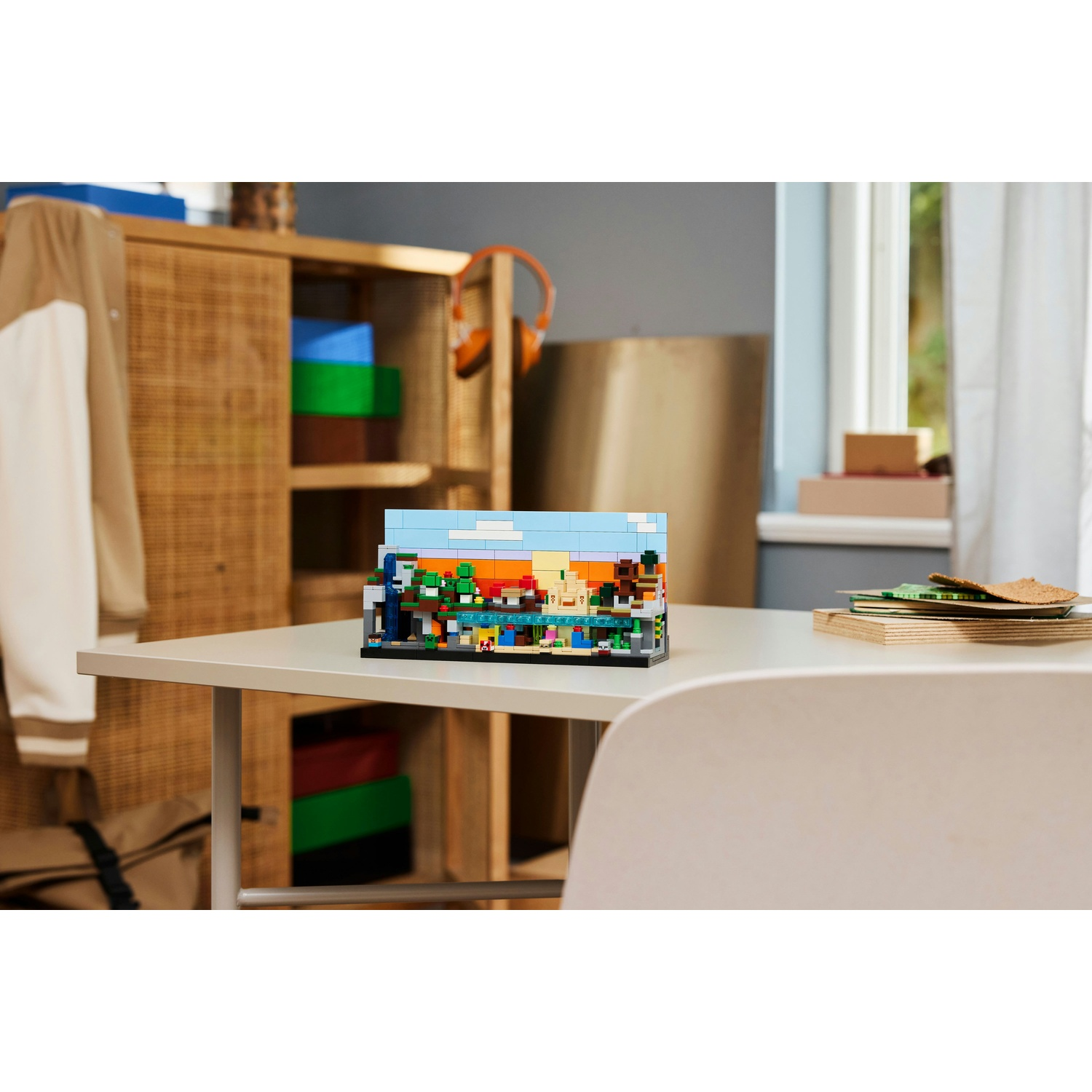 Un diorama Lego è su un tavolo bianco. Un armadio di legno e una finestra sono sullo sfondo. Le cuffie sono appese all'armadio.