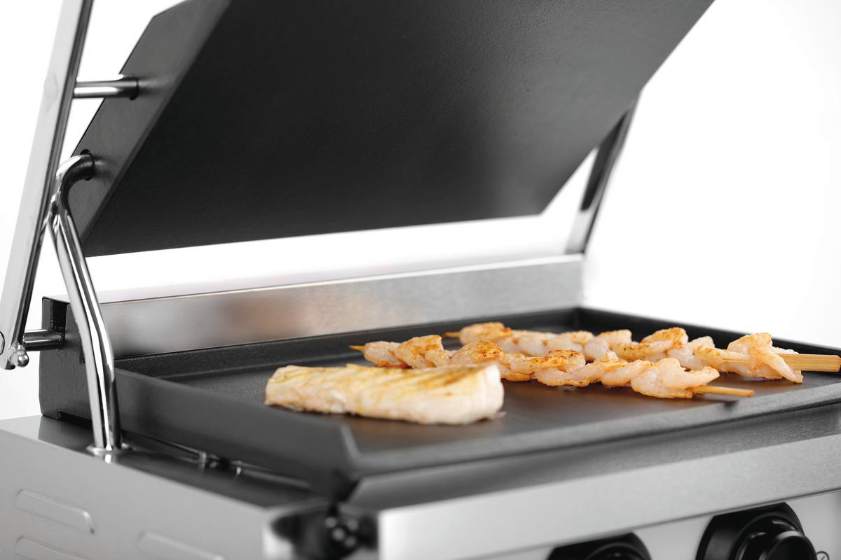 Ein Grill mit Garnesspießen und einem Fischstück. Der Grill ist offen und zeigt die Kochfläche. Edelstahl und Schwarz.