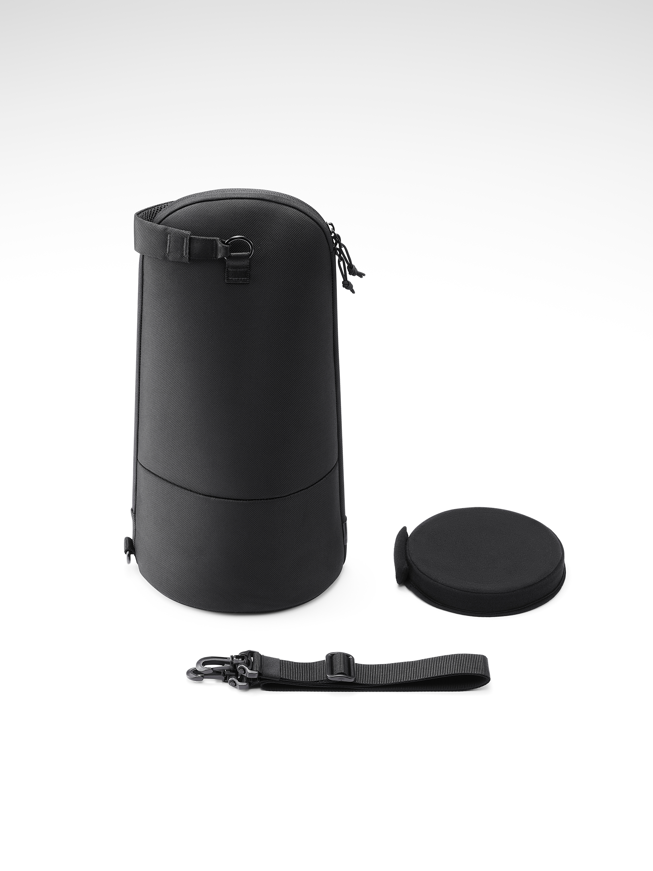 Borsa cilindrica nera, coperchio e cinturino su bianco. La borsa ha manico e zip. Il cinturino ha una clip.
