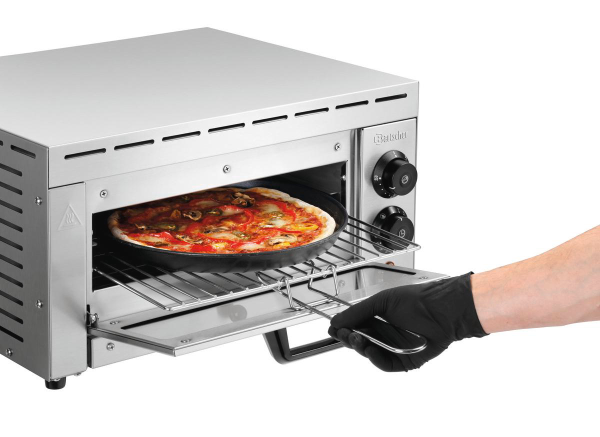 Eine Pizza in einem Ofen. Eine Hand mit einem schwarzen Handschuh zieht die Ablage heraus. Der Ofen ist aus Edelstahl.