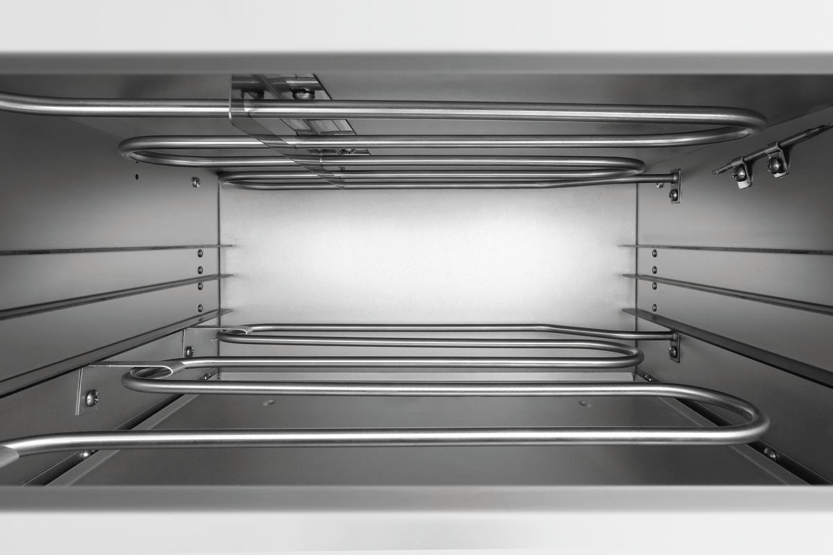 Innenansicht eines Ofens. Heizelemente sind sichtbar, zusammen mit Metallstützen und den Innenwänden des Ofens. Grau- und Silbertöne.