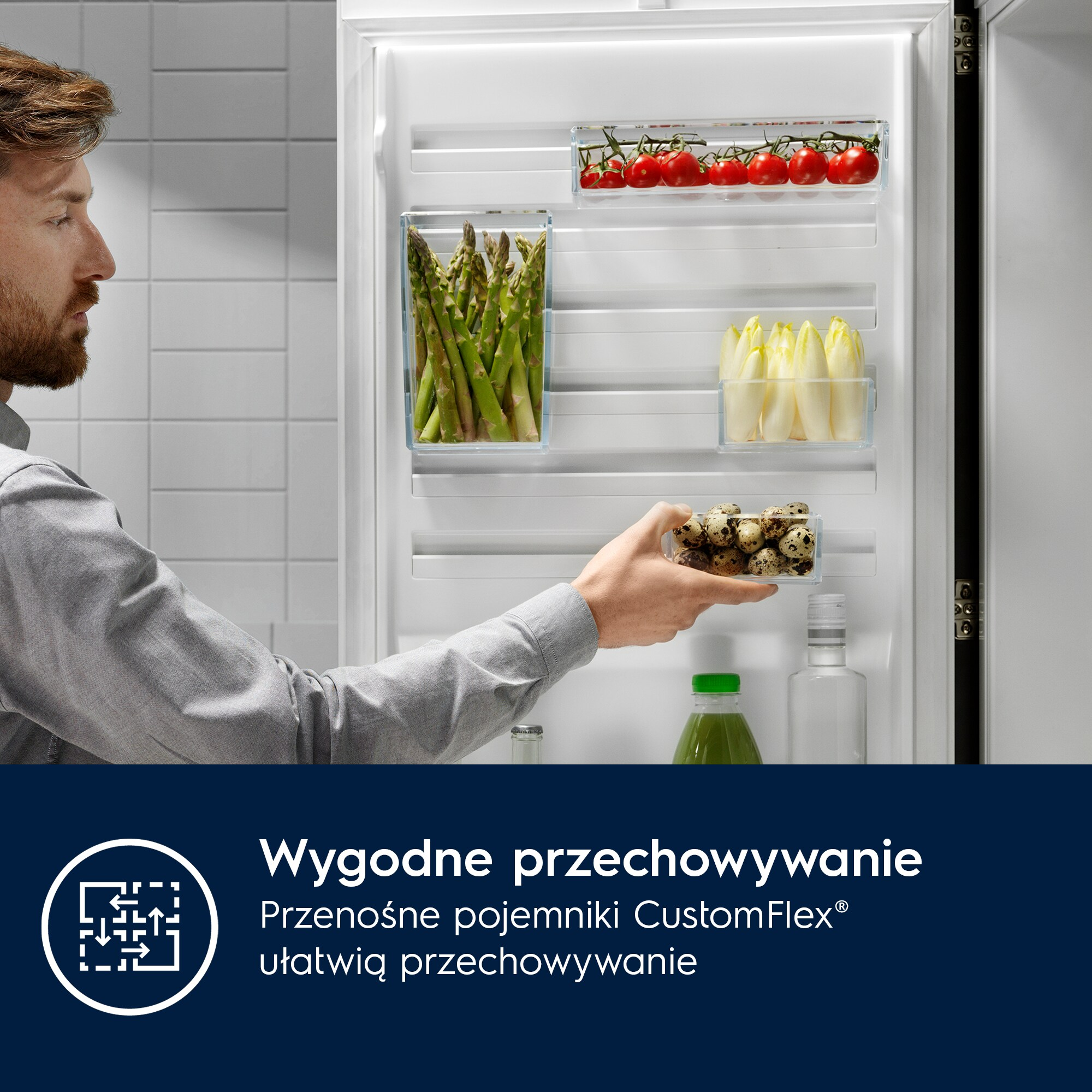 Mężczyzna otwiera lodówkę z warzywami i jajkami. W lodówce są pomidory, szparagi i endywia.