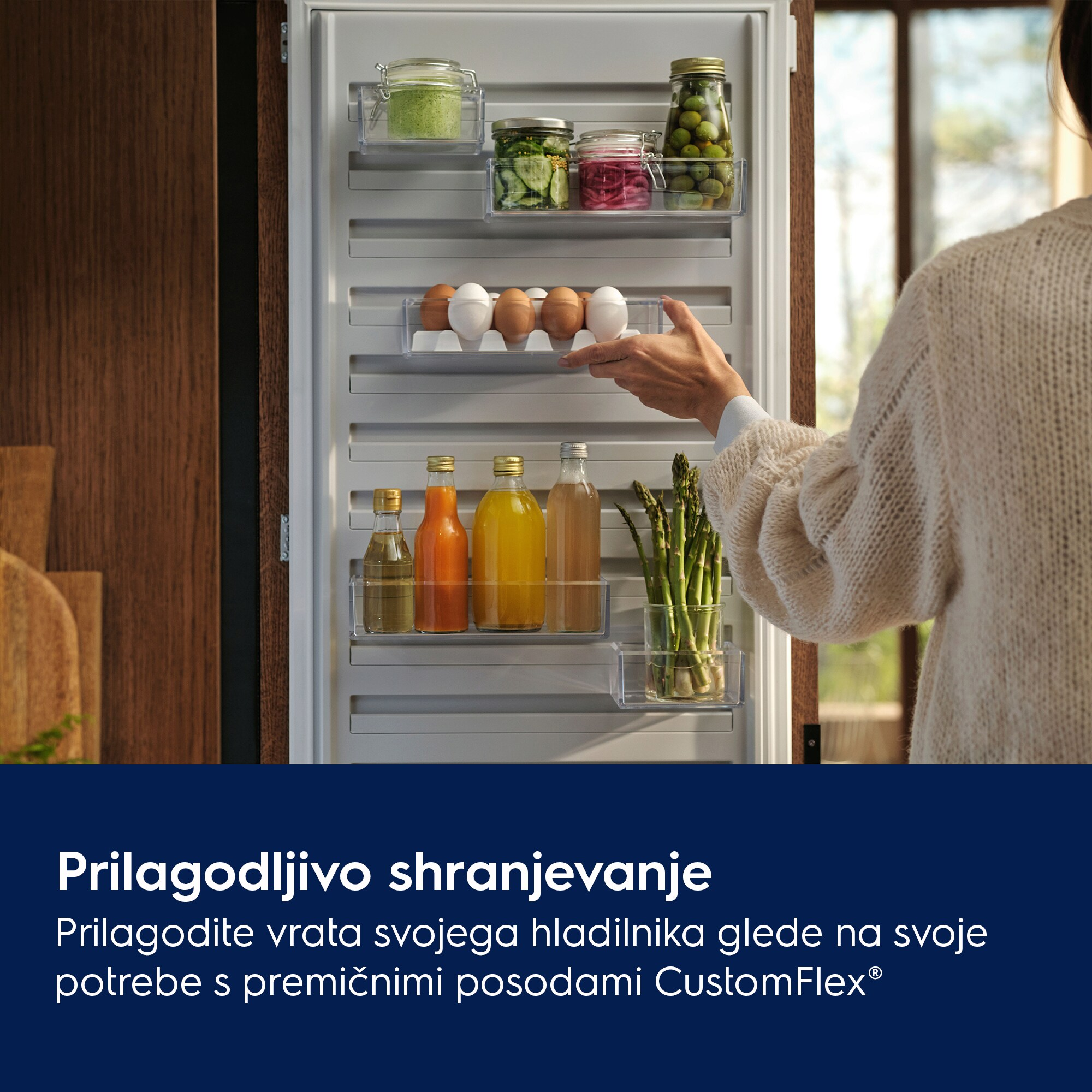 Kobieta otwiera drzwi lodówki wypełnionej jedzeniem. Słoiki z jedzeniem, jajka, butelki i szparagi.