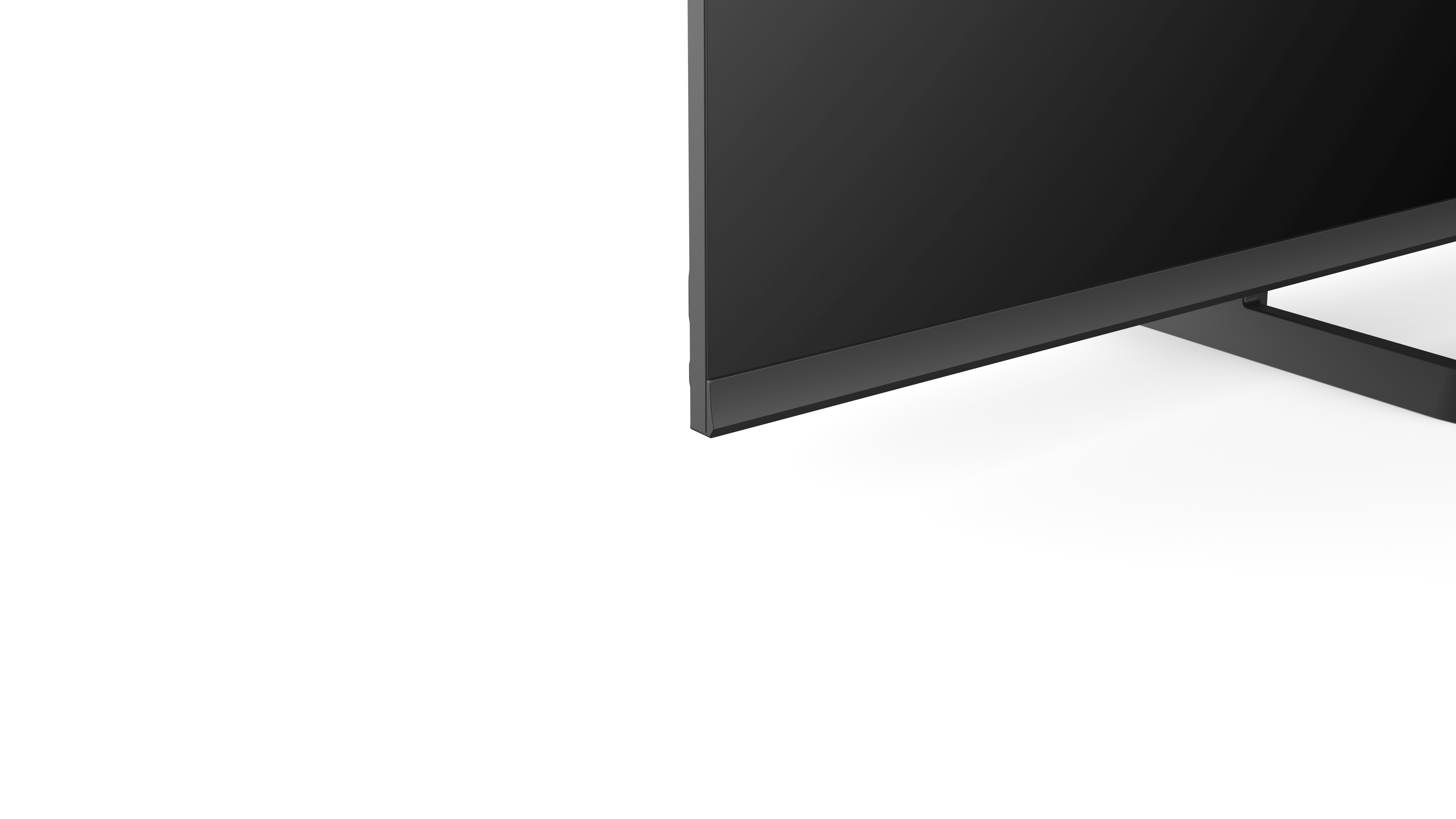 Czarny monitor z cienką ramką. Czarny stojak podtrzymuje monitor. Białe tło.