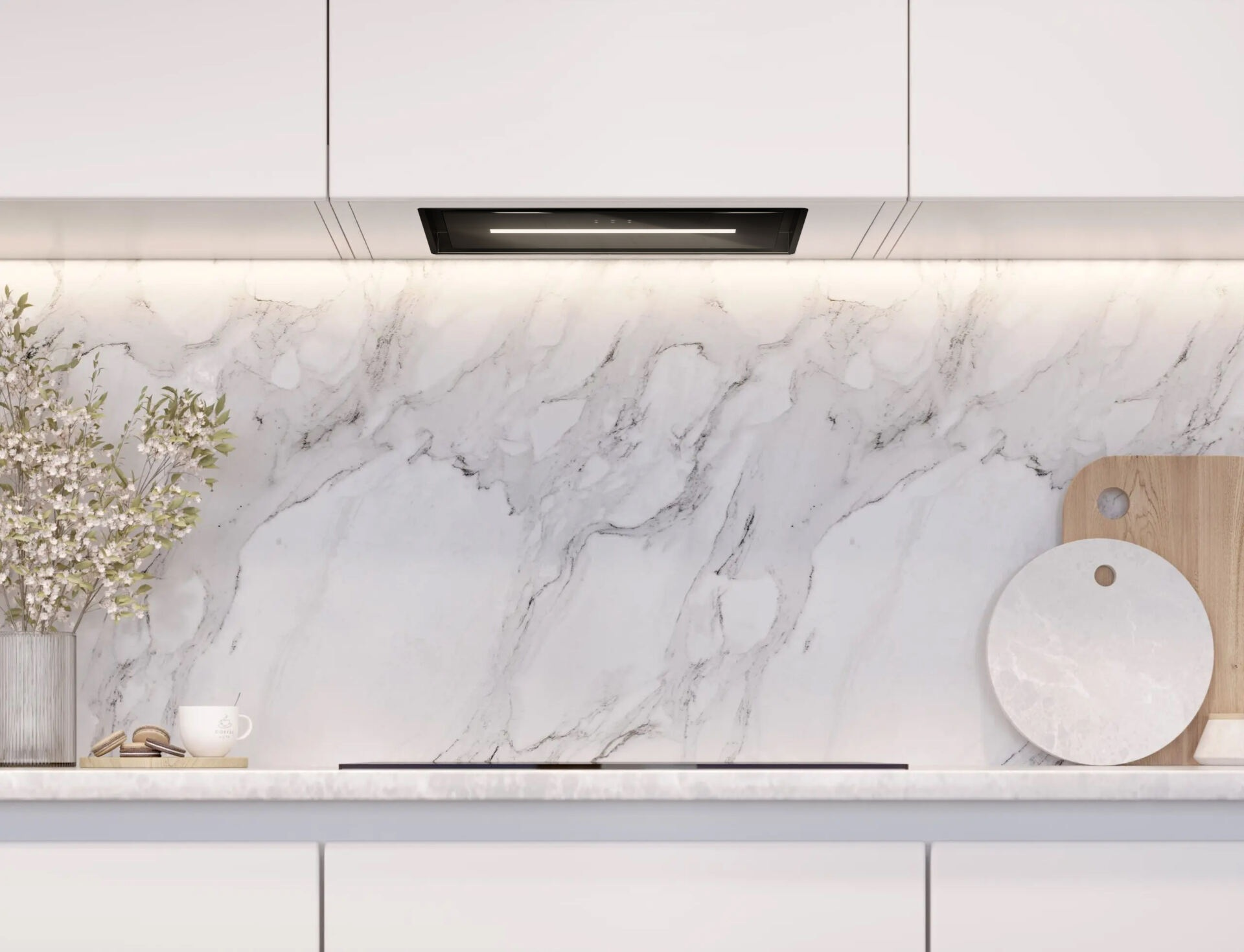 Nowoczesna kuchnia z białymi szafkami, marmurową ścianą, okapem, deskami do krojenia i filiżanką kawy.