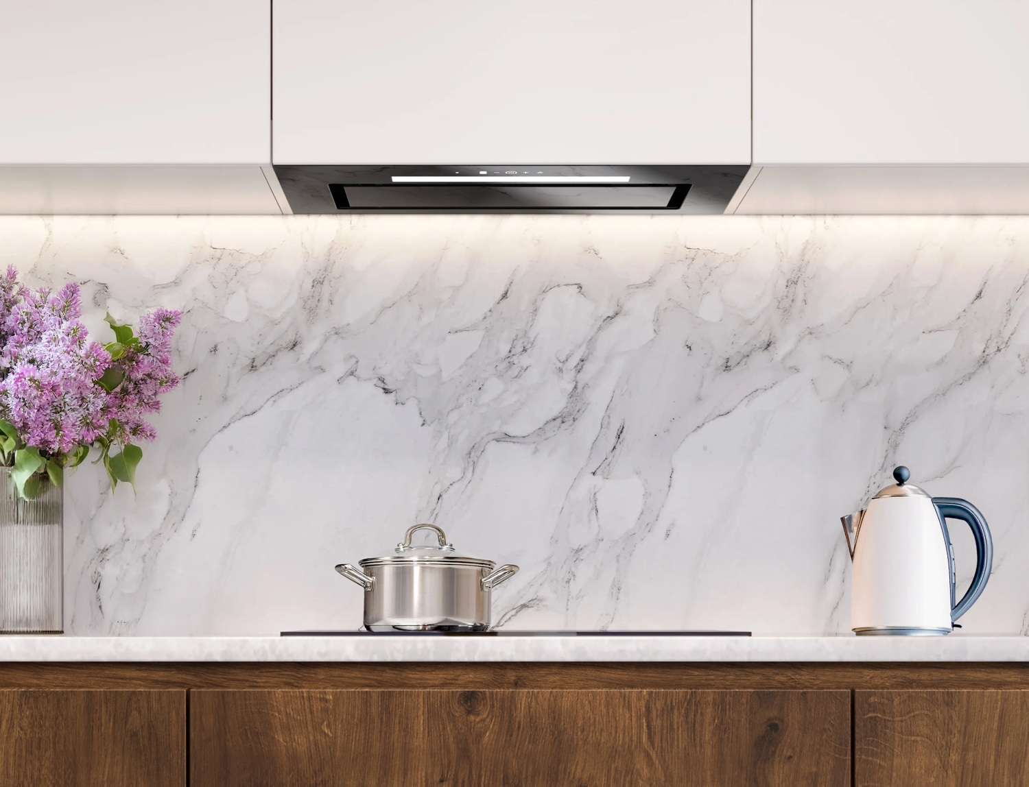 Kuchnia z marmurowym blatem, garnkiem ze stali nierdzewnej, białym czajnikiem z niebieskim uchwytem i wazonem z fioletowymi kwiatami.