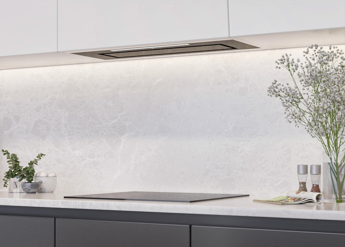 Nowoczesna kuchnia z białymi szafkami, marmurowym blatem, czarną płytą grzewczą i kwiatami w wazonie.