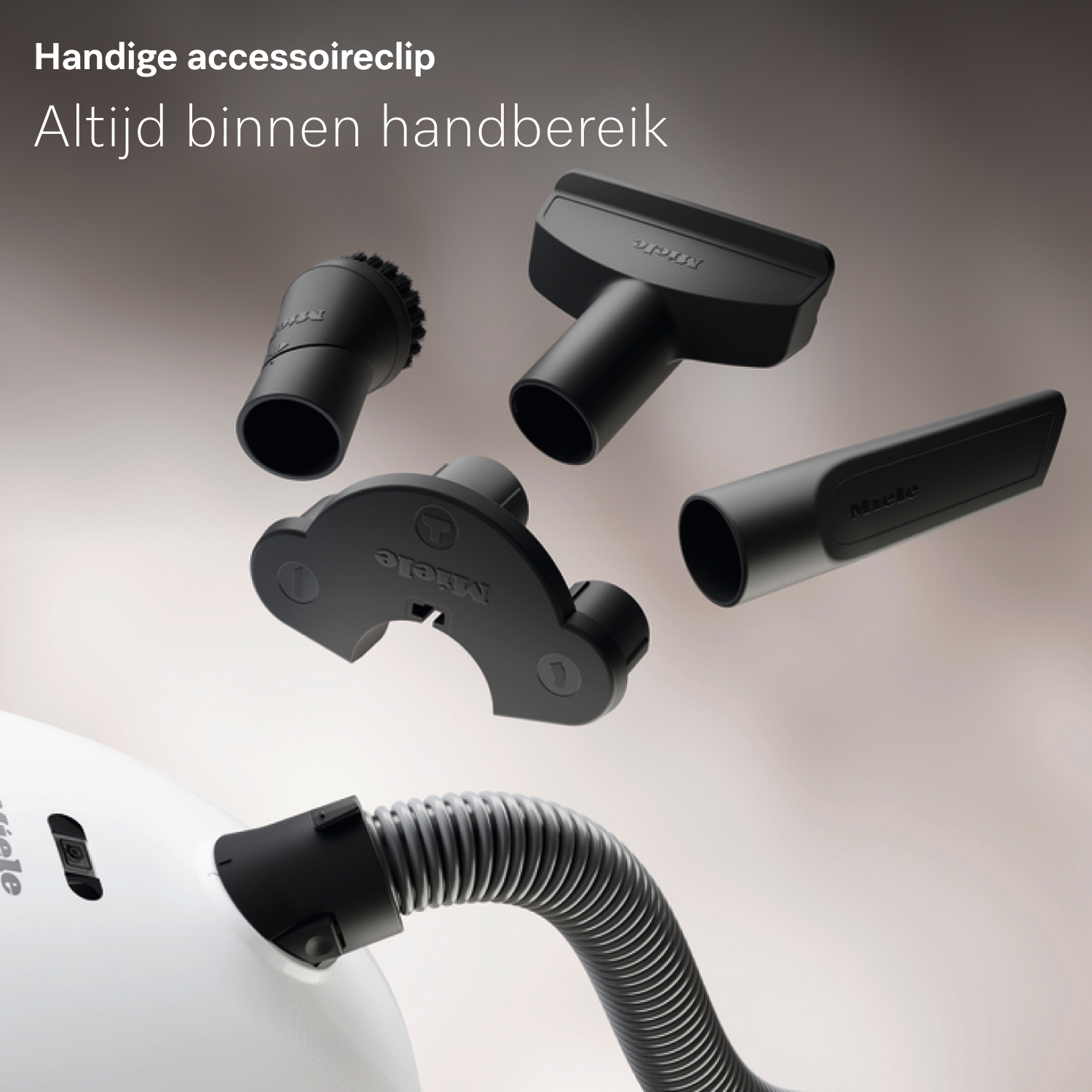 Zwarte stofzuigeraccessoires zweven boven een witte stofzuigerbehuizing met een slang. De tekst bovenaan luidt 'Handige accessoireclip'.