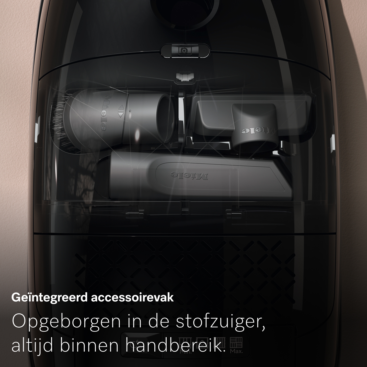 Black vacuum cleaner with transparent compartment. Contains accessories, Miele logo visible. Beige wall in the background.