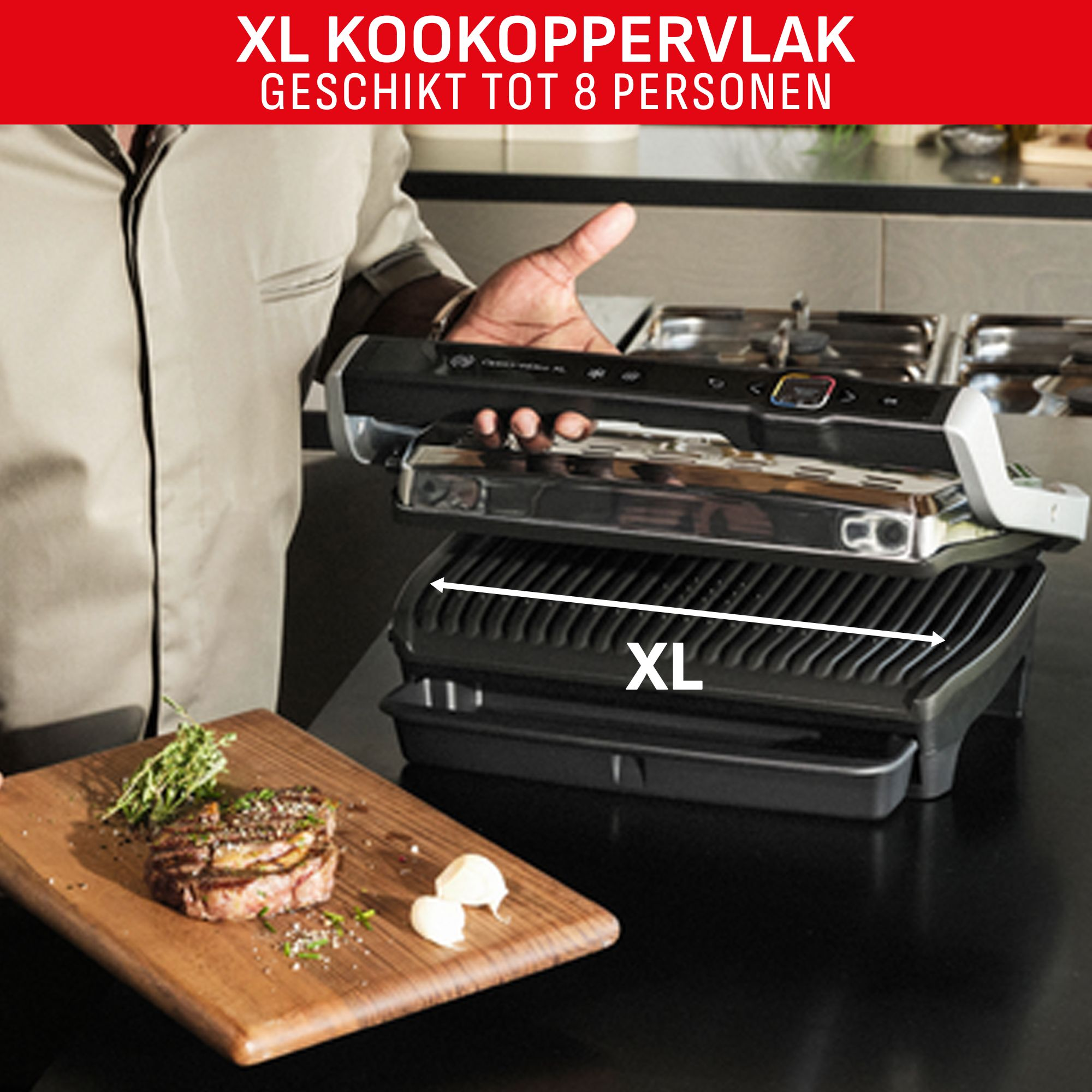 A person holding an XL grill. A wooden board with steak and garlic is in the foreground.