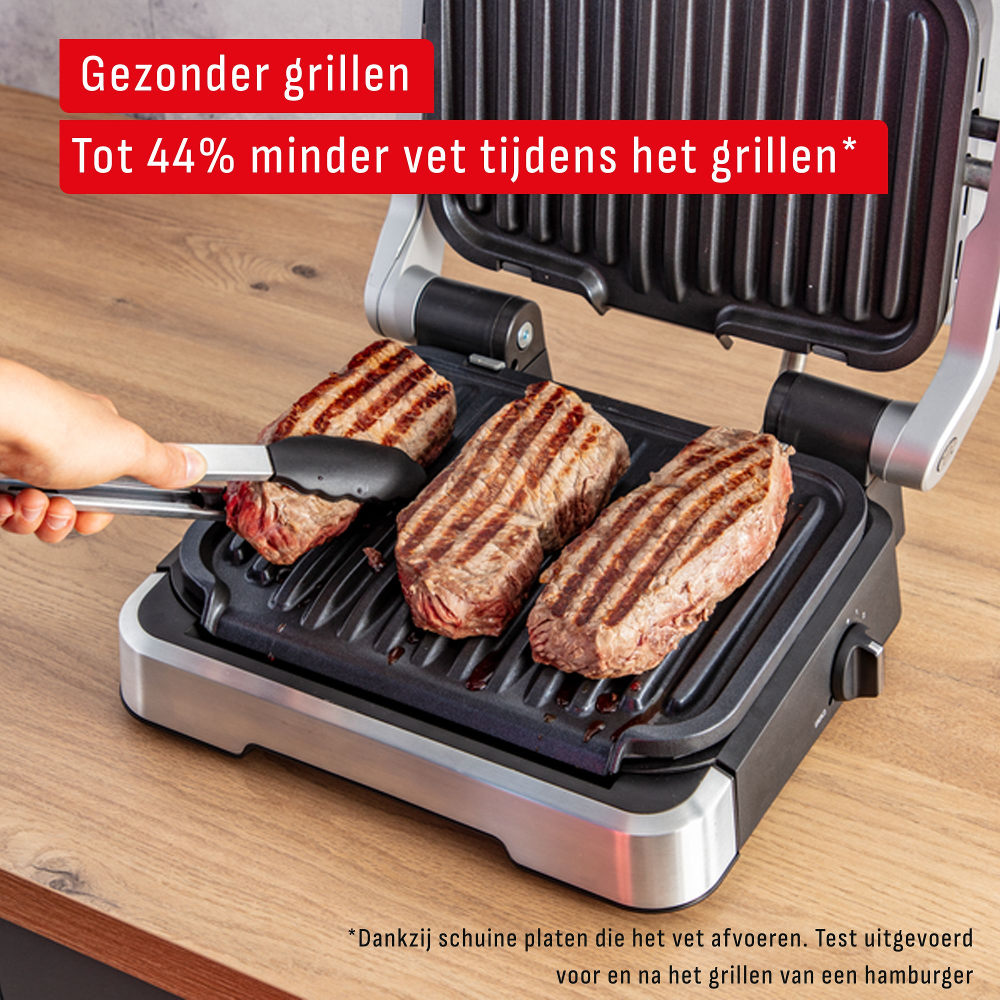 Een grill met drie steaks. Een hand houdt een tang vast die een steak verwijdert. Tekst luidt: 'Gezonder grillen, tot 44% minder vet'.