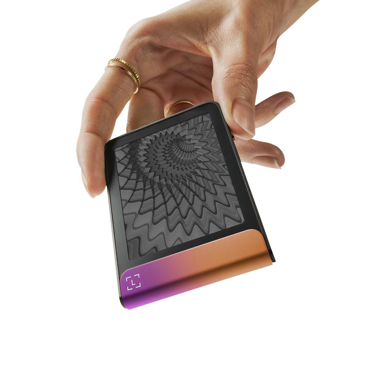 Una mano sostiene un dispositivo negro con una base degradada naranja-púrpura. La pantalla muestra un patrón gris arremolinado.
