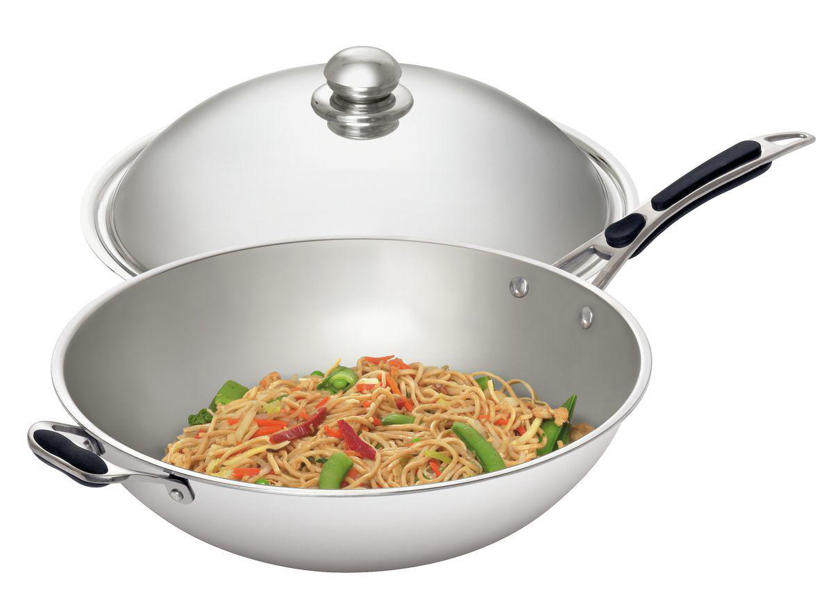 Eine Edelstahl-Wok-Pfanne mit Nudeln und Gemüse, der Deckel ist leicht angehoben. Schwarzer Griff an Seite und oben.