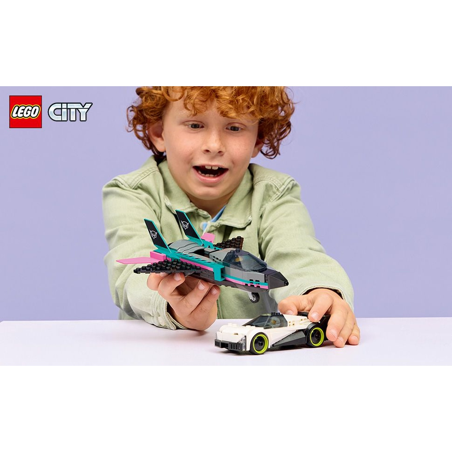 Un ragazzo tiene un jet e un'auto LEGO. Il jet è nero, verde acqua e rosa. L'auto è bianca e nera con ruote verde lime.