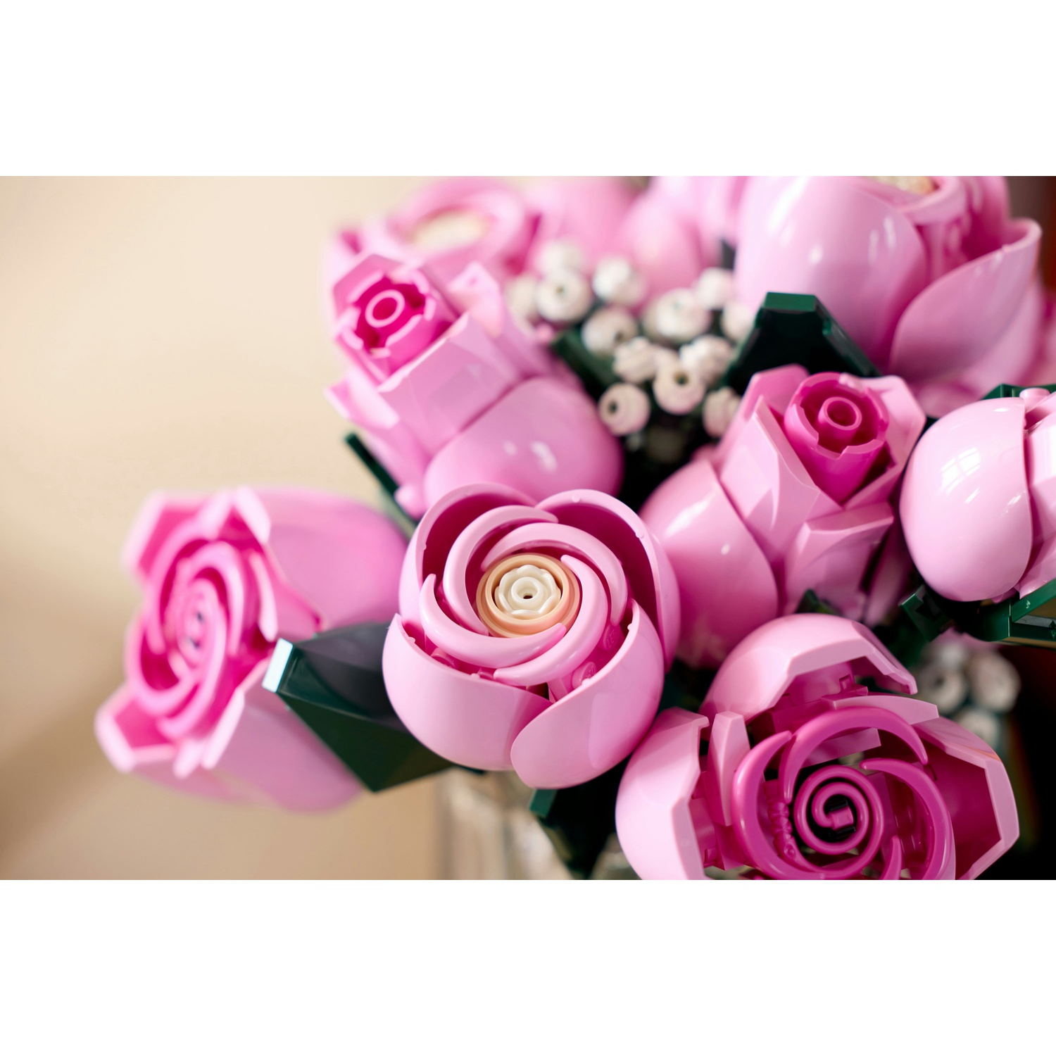 Un bouquet di rose Lego rosa. Le rose hanno un centro a spirale e foglie verdi. Lo sfondo è sfocato.