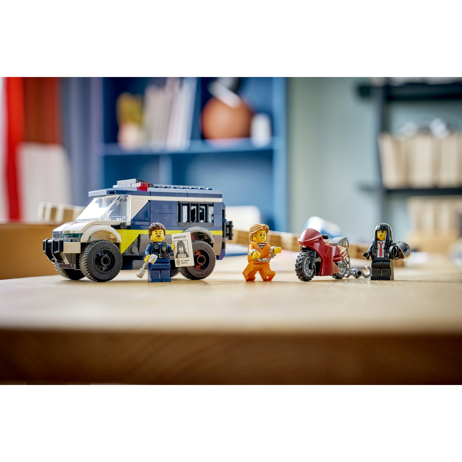 Set Lego della polizia: furgone della polizia, moto e tre minifigure. Un ufficiale, un prigioniero e una donna. Sfondo tavolo di legno.